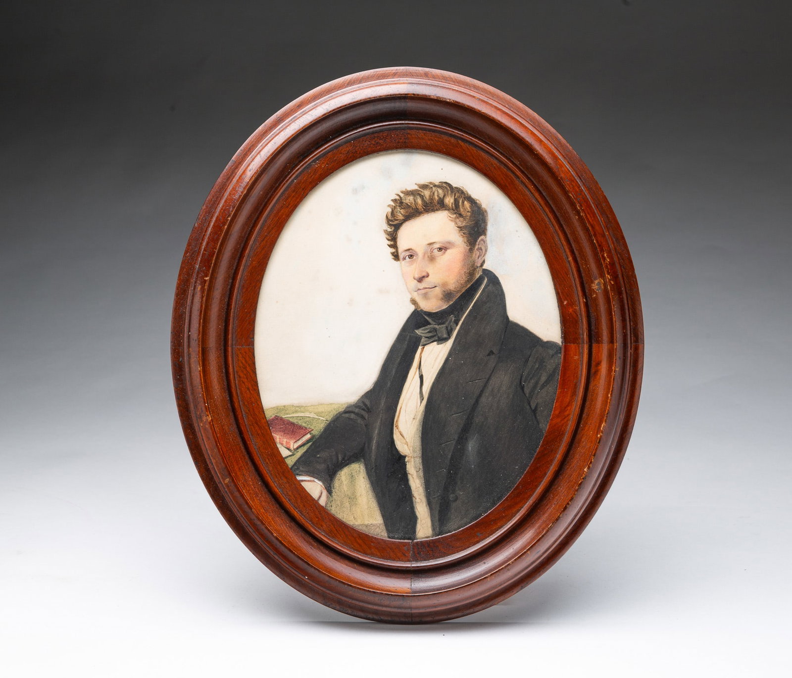 GOUACHE PORTRAIT OF A GENTLEMAN IN AN OVAL FRAME.: GOUACHE PORTRAIT OF A GENTLEMAN IN AN OVAL FRAME. American or English, 19th Century. On paper. He has wavy blond hair, mutton chops, and light brown eyes and wears a black tie, white shirt, white