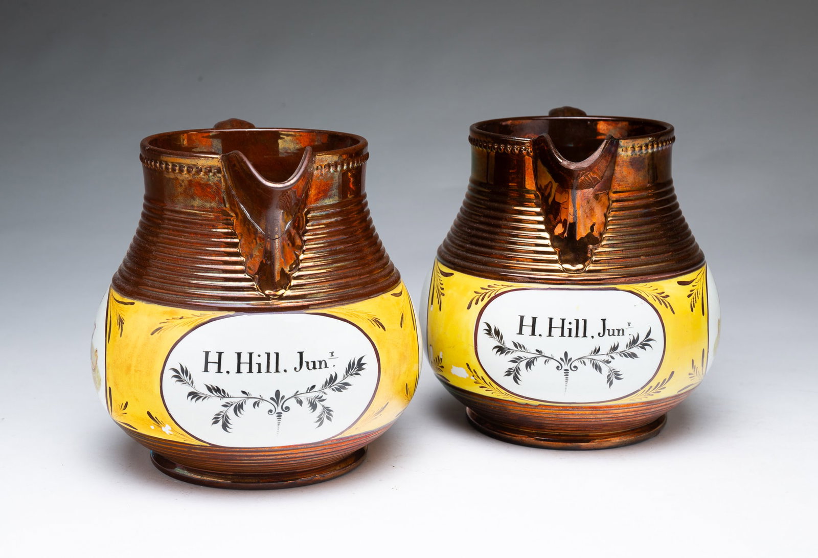 PAIR OF COPPER CANARY LUSTER JUGS MADE FOR HILAND HILL, JR. (CATSKILL, NEW YORK).: PAIR OF COPPER CANARY LUSTER JUGS MADE FOR HILAND HILL, JR. (CATSKILL, NEW YORK). American, 19th Century (ca. 1820). Having transfer-printed cartouches of a mother and child and the name "H. Hill,