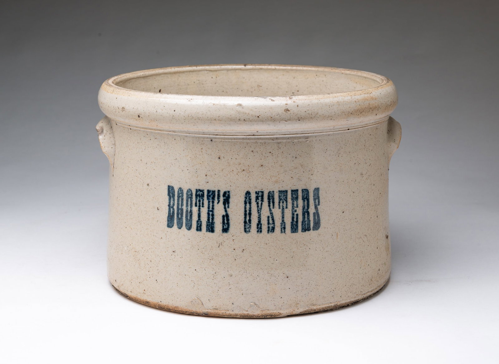 "BOOTH'S OYSTERS" COBALT-STAMPED STONEWARE CROCK.: "BOOTH'S OYSTERS" COBALT-STAMPED STONEWARE CROCK. American, Late 19th Century. Salt-glazed stoneware crock with two lug handles and a pronounced top rim, stenciled with "Booth's Oysters" in blue. 8"h.
