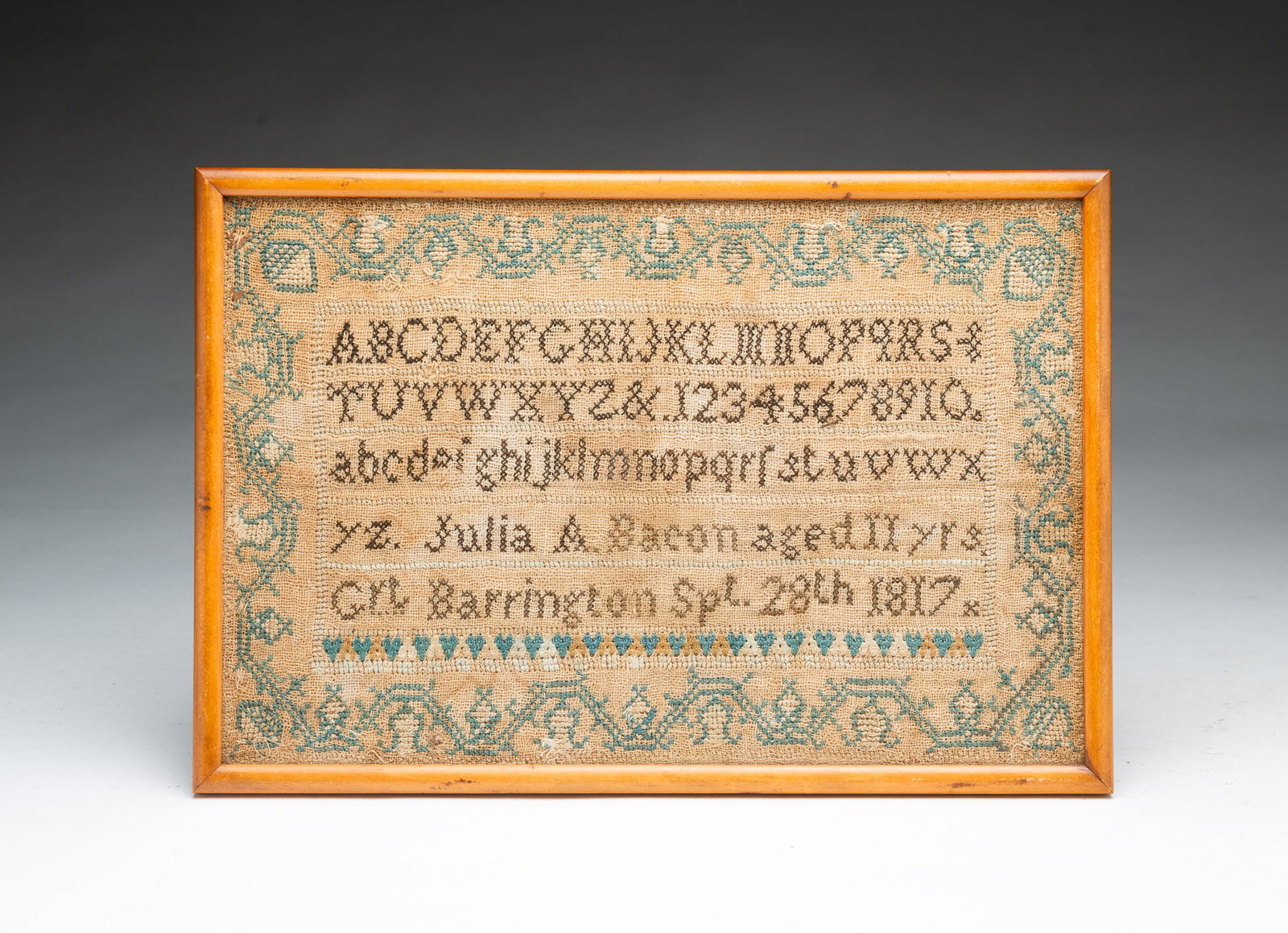 JULIA A. BACON NEEDLEWORK SAMPLER DATED 1817.: JULIA A. BACON NEEDLEWORK SAMPLER DATED 1817. American. Strawberry border, alphabet, and across bottom "Julia A. Bacon, aged 11 yrs, Grt. Barrington Spt 28th 1817". In a contemporary frame, 8.5"h.