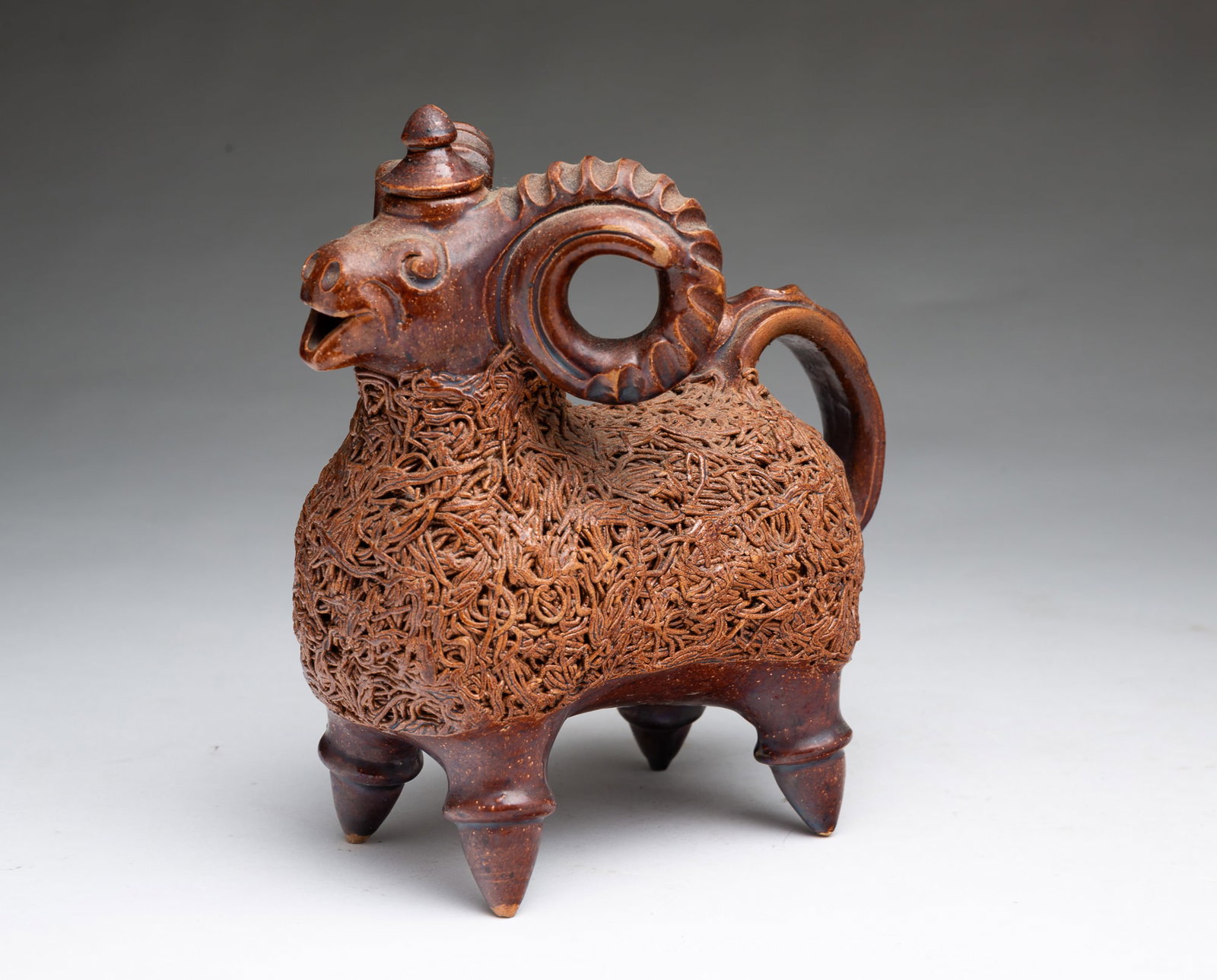 GLAZED CERAMIC RAM DECANTER WITH COLESLAW-DECORATED BODY.: GLAZED CERAMIC RAM DECANTER WITH COLESLAW-DECORATED BODY. European, 20th Century. Standing ram figure with pronounced horns and tail handle, lid on top of head, open mouth, tapered legs, and coleslaw
