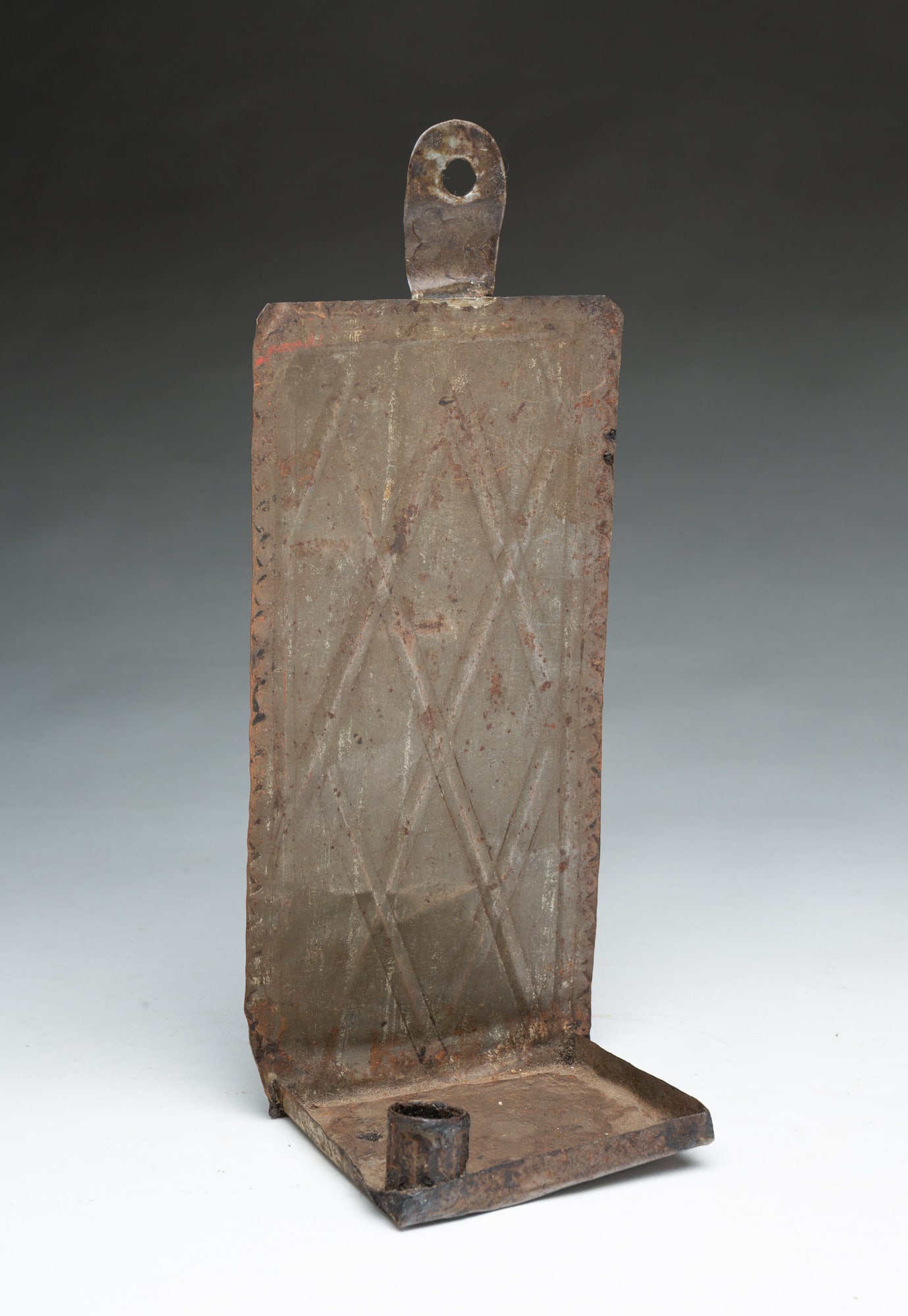EMBOSSED TIN CANDLE SCONCE.: EMBOSSED TIN CANDLE SCONCE. American, 19th Century. Hanging hole at top, rectangular back with scalloped edges and diamond pattern, square pan with folded up edges and a single candle socket at front