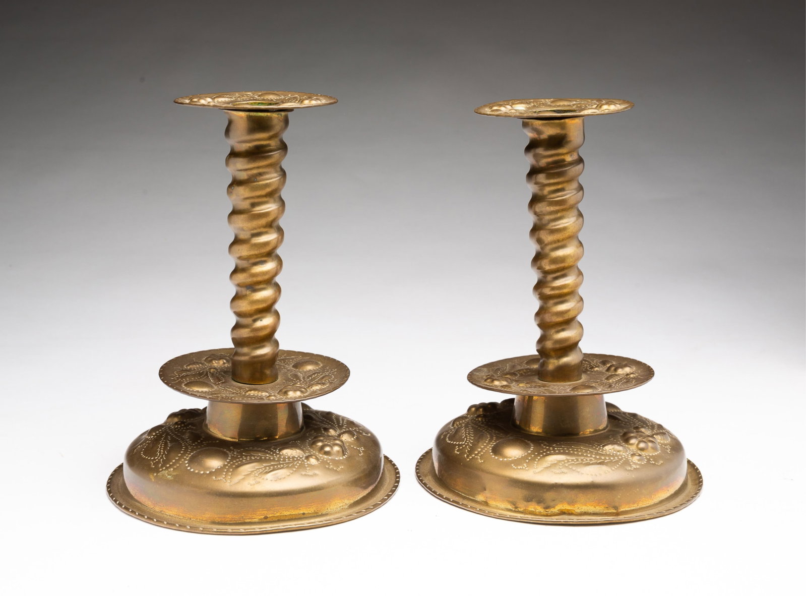 PAIR OF W. BRATT JONKOPING (SWEDEN) REPOUSSE-DECORATED BRASS CANDLESTICKS. (1 of 5)
