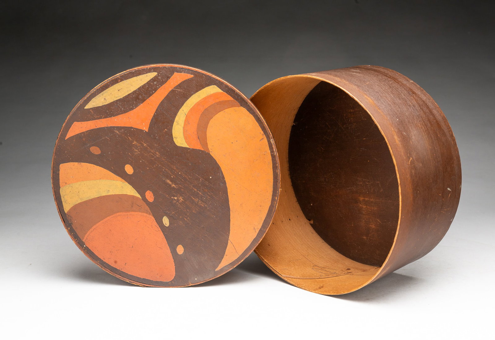 LARGE PAINTED BENTWOOD PANTRY BOX WITH ABSTRACT POLYCHROME DECORATION.: LARGE PAINTED BENTWOOD PANTRY BOX WITH ABSTRACT POLYCHROME DECORATION. American, 19th Century. Of circular form with lapped bands and copper tacks, painted brown, the lid having a colorful swirl,