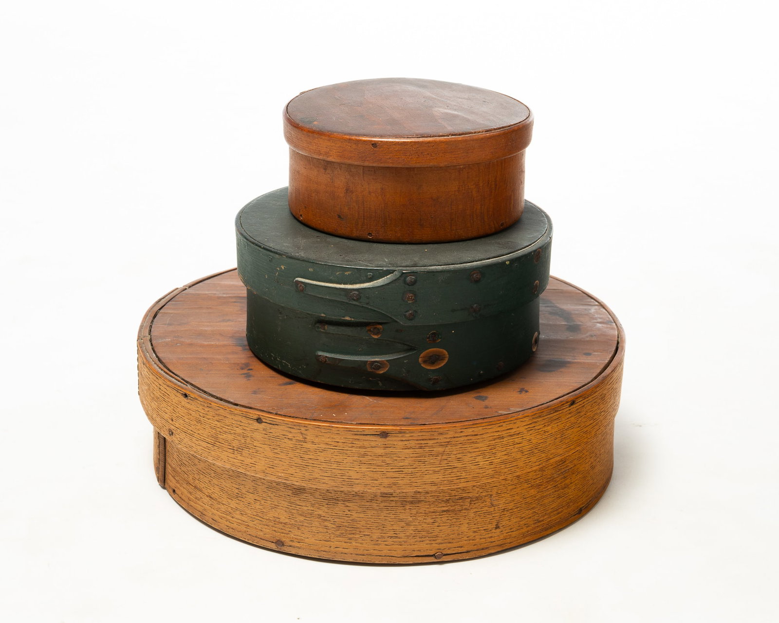 THREE ROUND BENTWOOD PANTRY BOXES.: THREE ROUND BENTWOOD PANTRY BOXES. American, 19th Century. Largest in natural finish with sewn seams, 3.75"h. 12"d., middle in dark green paint, Harvard joints and square nails, 3"h. 7.5"d., and the