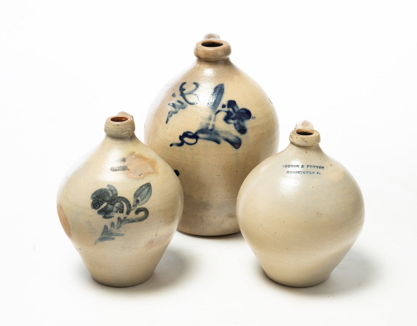 THREE FREEHAND COBALT DECORATED OVOID STONEWARE JUGS WITH APPLIED HANDLES.: THREE FREEHAND COBALT DECORATED OVOID STONEWARE JUGS WITH APPLIED HANDLES. American, 19th Century. A three-gallon jug with brushed cobalt floral decoration; a "NORTON & FENTON / BENNINGTON Vt" jug wit
