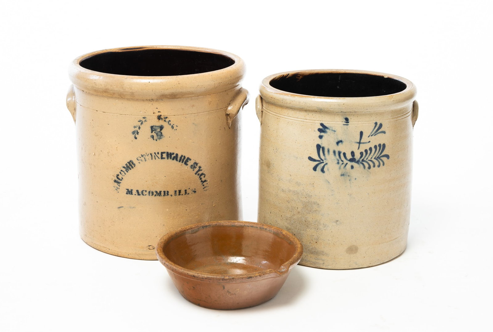THREE STONEWARE VESSELS.: THREE STONEWARE VESSELS. American, second half 19th Century. A milk pan with rolled rim, nicely formed spout, canted sides, and chocolate brown glaze. 2.75"h. 9"d. A five-gallon crock with applied han