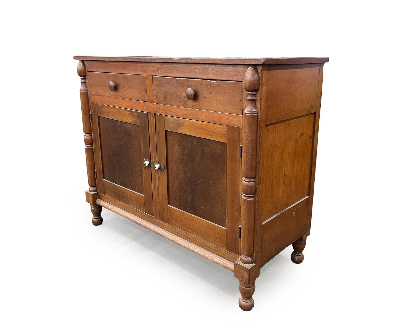 TRANSITIONAL CHERRY SIDEBOARD.: TRANSITIONAL CHERRY SIDEBOARD. American, Second quarter 19th Century. Poplar secondary. Sheraton to Empire. Two-board top, paneled ends, turned half pilasters, two dovetailed drawers over two single p