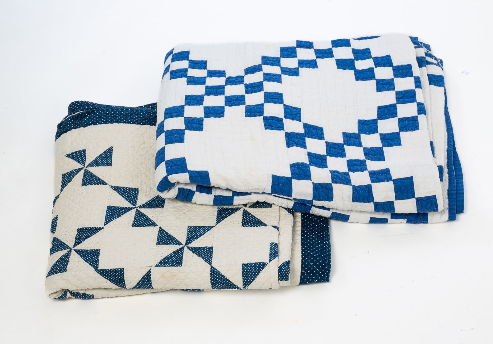 TWO BLUE AND WHITE PIECE WORK QUILTS.: TWO BLUE AND WHITE PIECE WORK QUILTS. American, First half 20th Century. Cotton. Pinwheel pattern, solid white background with blue and white patterned fabrics. 70"w. 74"l. and small squares with