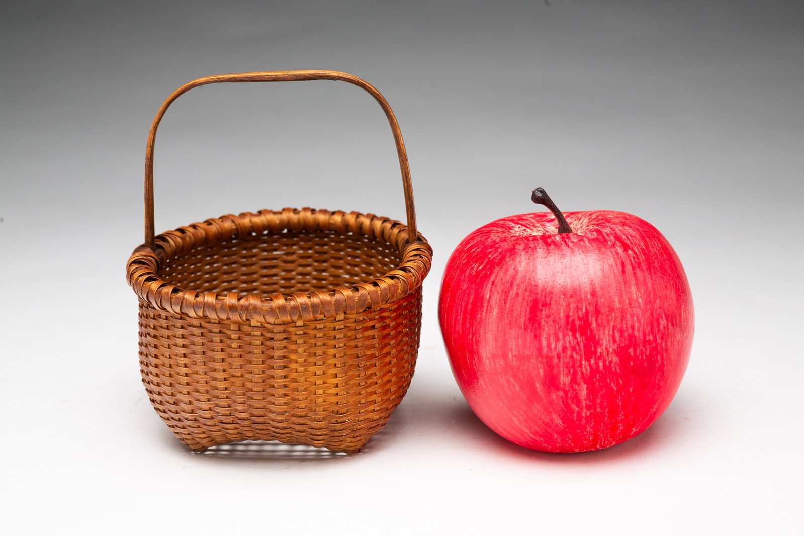 FINE MINIATURE WOVEN SPLINT "CAT HEAD" BASKET.: FINE MINIATURE WOVEN SPLINT "CAT HEAD" BASKET. American, Early 20th Century. Finely woven splint "cat head" form basket with a stationary bentwood handle and wrapped rim. Nice old patina. 4.75"h. 4"w.