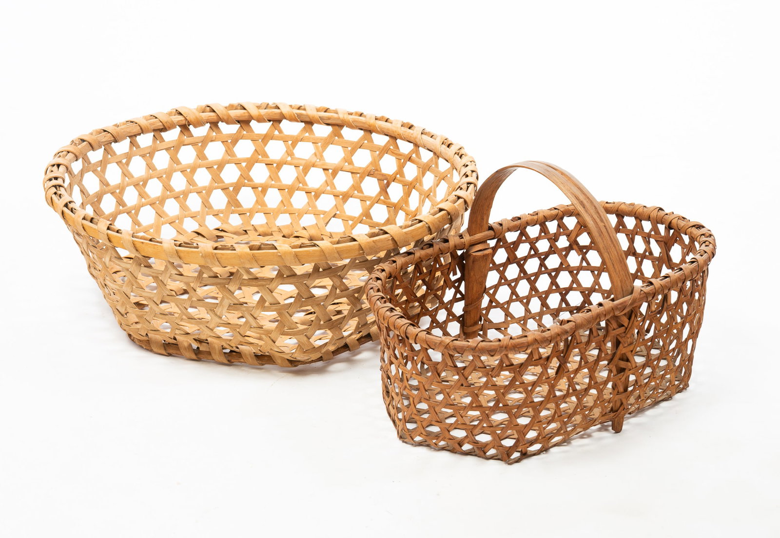 TWO FINELY WOVEN CHEESE BASKETS.: TWO FINELY WOVEN CHEESE BASKETS. American, Late 19th Century. Oak. Lozenge shape with handle, 9.5"h. and round, 6"h. 10.25"d. Larger is Ex Clark Garrett (Fairhaven, Ohio). Provenance: The Lifetime