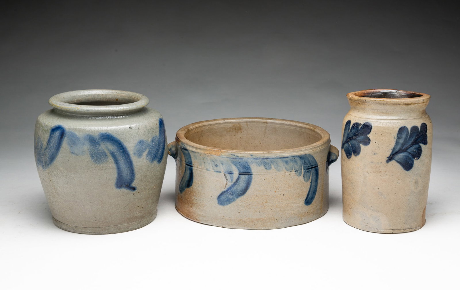 THREE COBALT-DECORATED STONEWARE JARS.: THREE COBALT-DECORATED STONEWARE JARS. American, Second half 19th century. A butter crock with applied lug handles, incised banding, and cobalt flourishes, 4.25"h. 9.75"w., a canning jar with pronounc