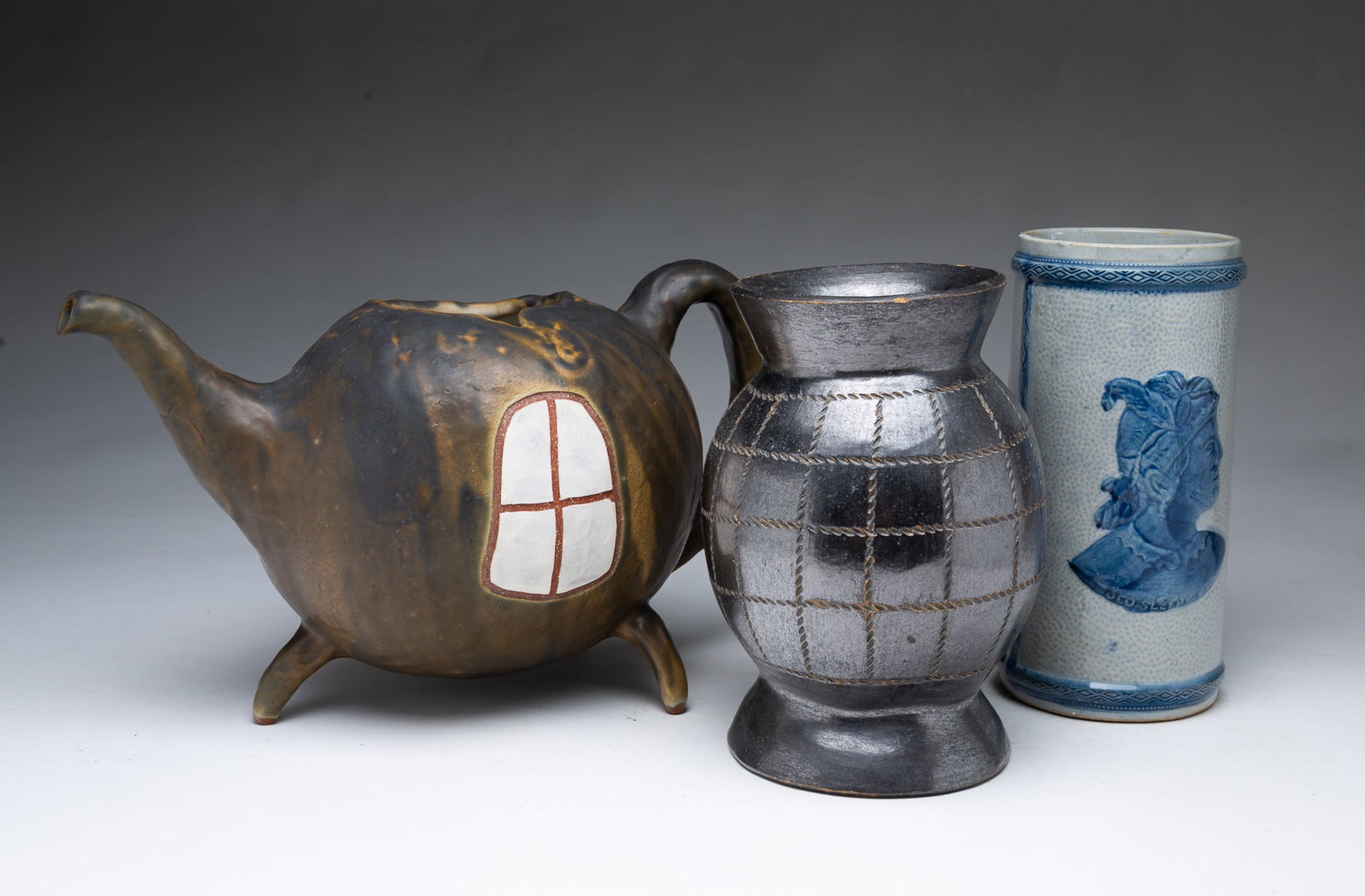 OLD SLEEPY EYE (SLEEPY EYE, MINNESOTA) BLUE AND WHITE STONEWARE VASE, A METALLIC-GLAZED VASE, AND A: OLD SLEEPY EYE (SLEEPY EYE, MINNESOTA) BLUE AND WHITE STONEWARE VASE, A METALLIC-GLAZED VASE, AND A TEAPOT PLANTER. American, Early 20th Century. Of cylindrical form, decorated with Sioux Chief