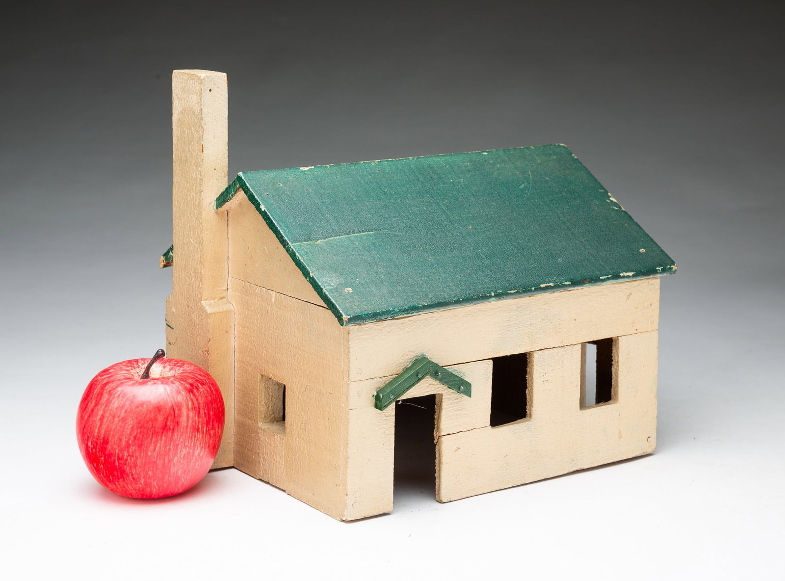 FOLKSY MINIATURE GREEN AND TAN PAINTED WOODEN HOUSE.: FOLKSY MINIATURE GREEN AND TAN PAINTED WOODEN HOUSE. American, 20th Century. Simple construction, having a green roof and tan sides with cutout windows and an applied chimney. 9"h. 8"w. 9"d.