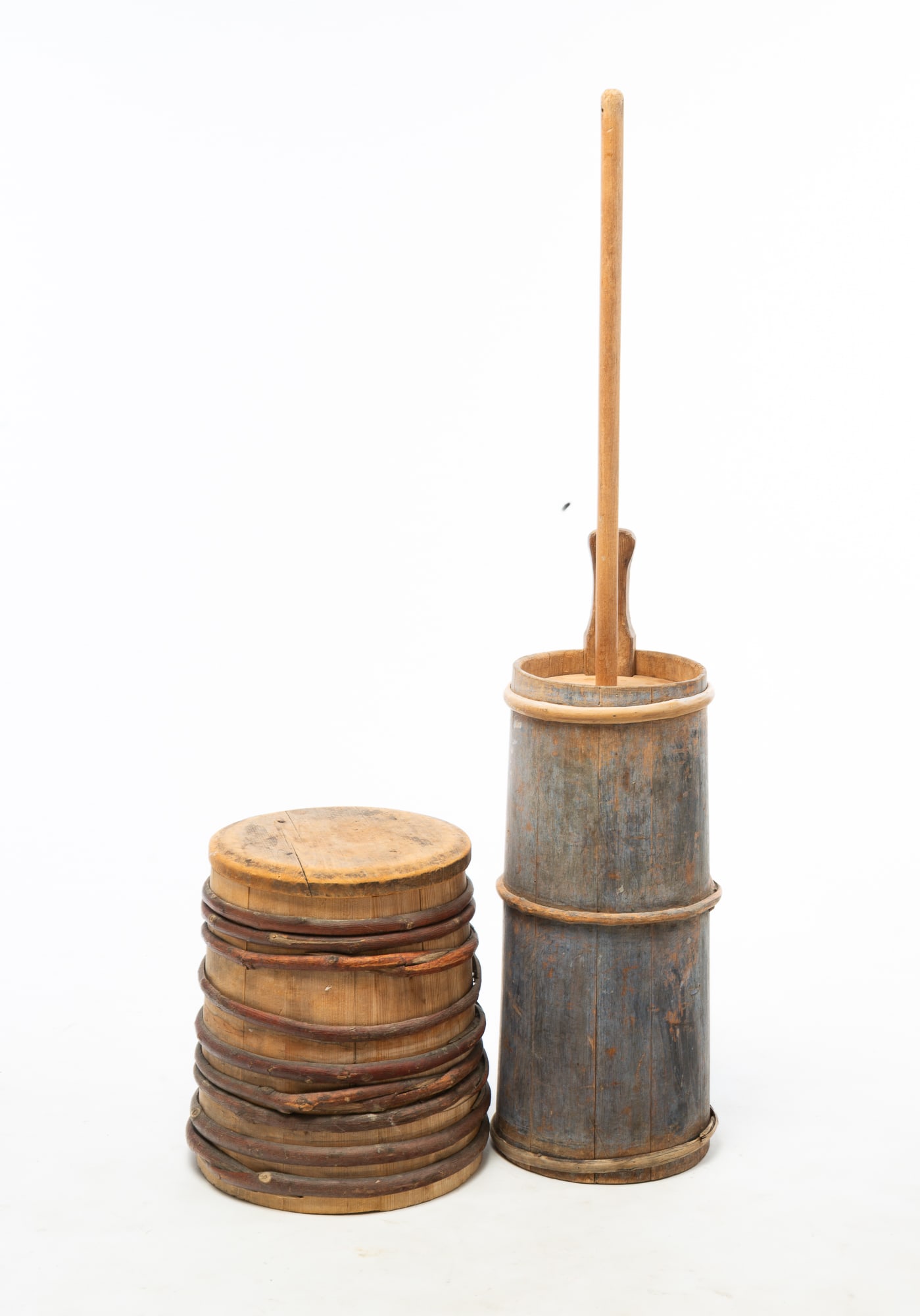 STAVE CONSTRUCTED BUTTER CHURN AND LIDDED BUCKET.: STAVE CONSTRUCTED BUTTER CHURN AND LIDDED BUCKET. American, 19th Century. Pine. Both have grapevine hoops. A piggin churn with original blue paint, 46"h., and bucket with slightly canted sides, 15"h.