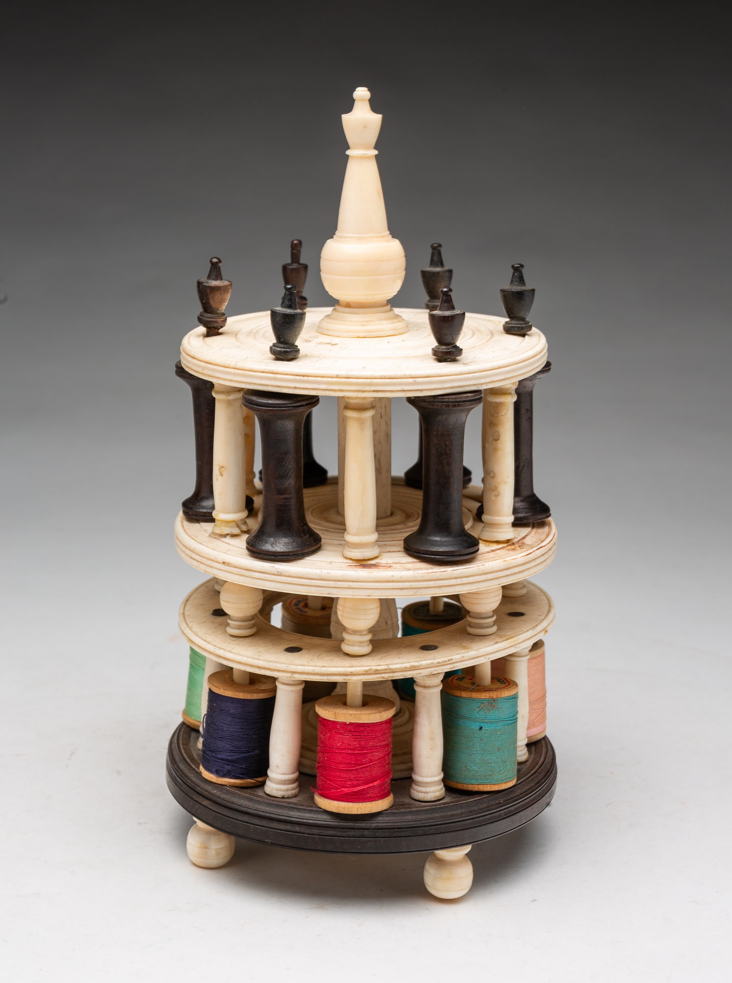 TWO-TIER CLASSICAL SAILOR ART SPOOL CADDY.: TWO-TIER CLASSICAL SAILOR ART SPOOL CADDY. American, 19th Century. Panbone and ebony. Elaborate circular colonnade with Doric columns and ebony spools, surmounted by turned urn-form finials, and a