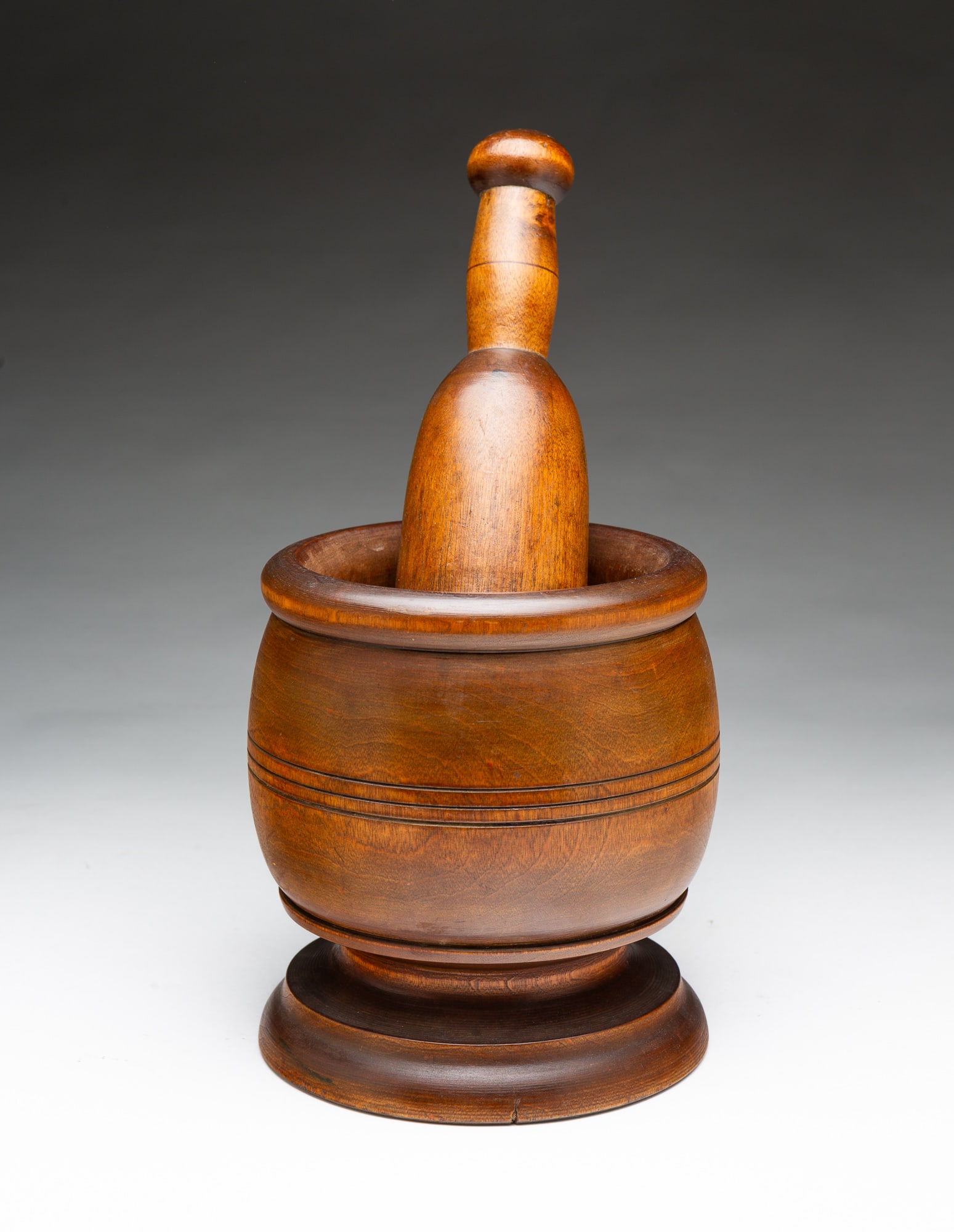 TREENWARE MORTAR AND PESTLE.: TREENWARE MORTAR AND PESTLE. American, Early 20th Century. Maple. Mortar with nice, pronounced foot, bulbous body with incised banding, and rolled lip, 6.75"h. And pestle in typical form with knob