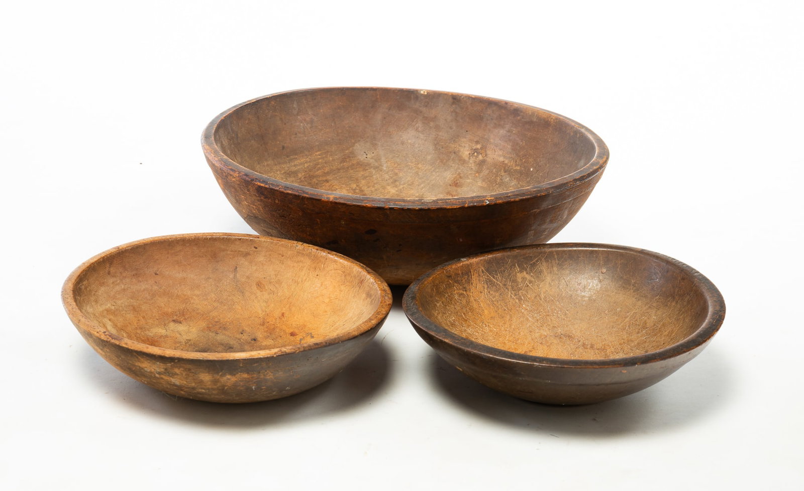 THREE TURNED WOOD BOWLS.: THREE TURNED WOOD BOWLS. American, 19th Century. Turned bowls, slightly out of round, with nice surfaces. Largest with repaired side, 6"h. One with slightly pronounced lip, 19.5"w. 3.5"h. 13.5"w. And