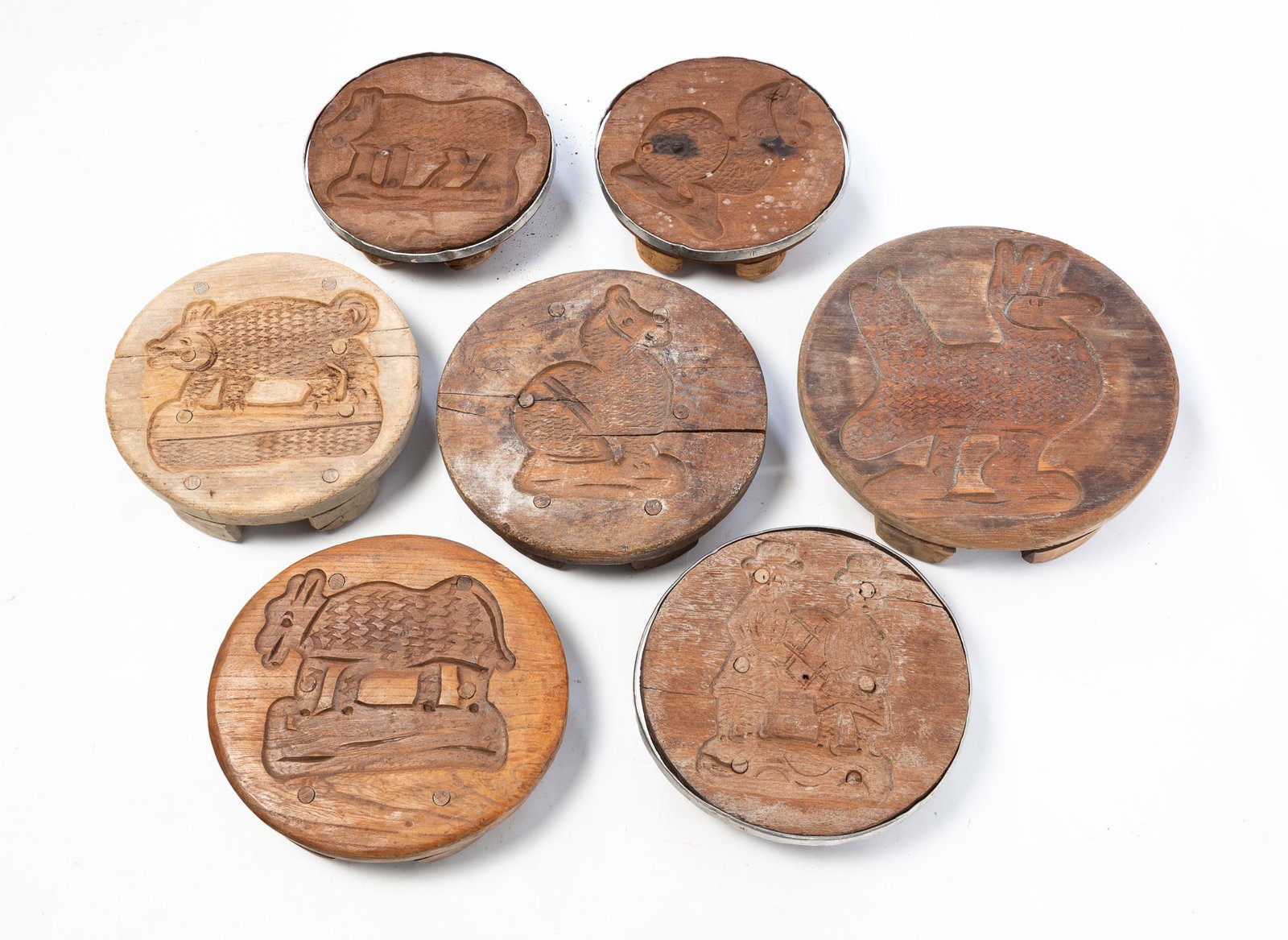 SEVEN CARVED WOOD FIGURAL CHEESE PRESSES.: SEVEN CARVED WOOD FIGURAL CHEESE PRESSES. American, Late 19th or Early 20th Century. Mixed woods. Comprising round examples with relief-carved animals and figures. One, 3"h. 14.25"d. Provenance: The