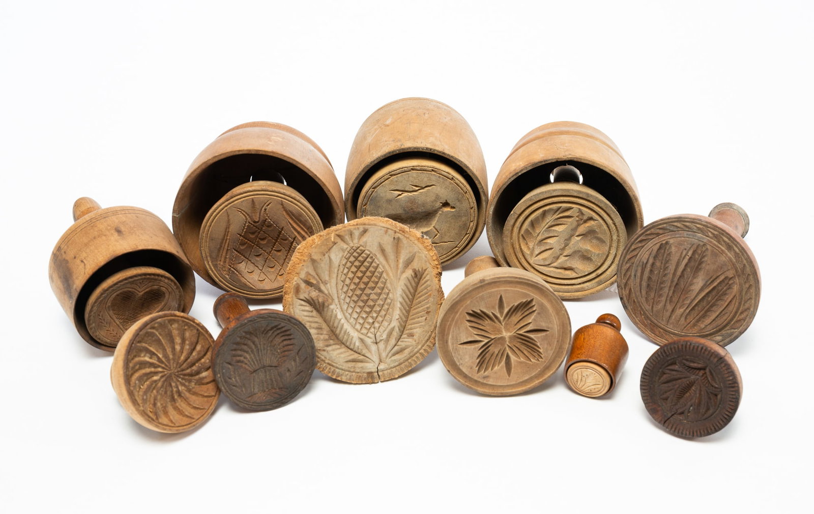 ELEVEN CARVED WOOD BUTTER STAMPS.: ELEVEN CARVED WOOD BUTTER STAMPS. American, 19th Century. Mixed woods. Comprising a variety of relief-carved designs, including a heart, a cow, wheat, and pineapples. Largest, 6"h. Provenance: The