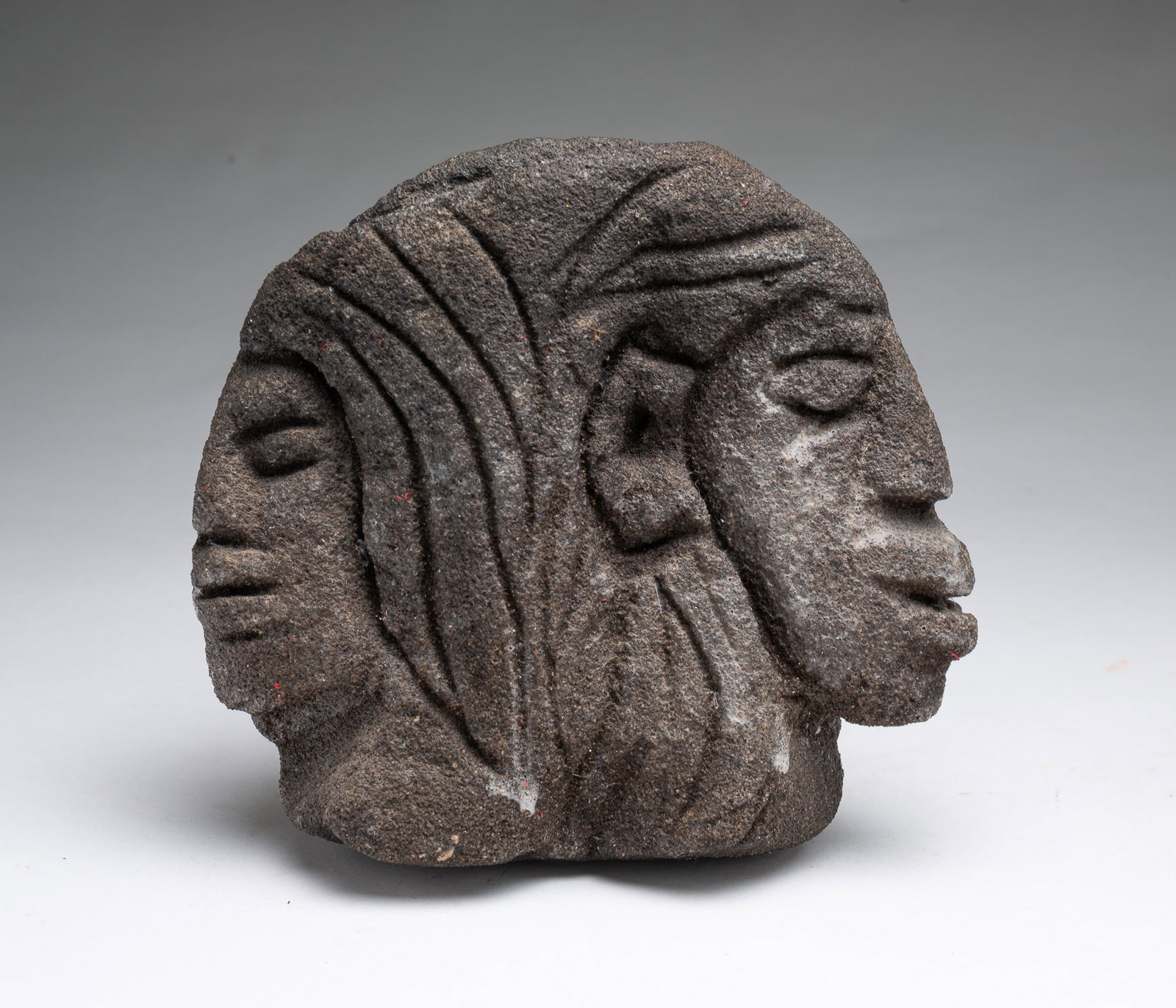 ATTRIBUTED TO LONNIE HOLLEY (ALABAMA, B. 1950) CARVED SANDSTONE SCULPTURE WITH TWO FACES AND: ATTRIBUTED TO LONNIE HOLLEY (ALABAMA, B. 1950) CARVED SANDSTONE SCULPTURE WITH TWO FACES AND ELEPHANT. American, 20th Century. Dark sandstone carving depicting two faces on front and an upside-down el