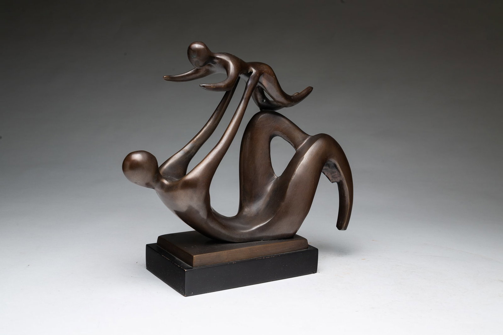 BRONZE STATUE OF MOTHER AND CHILD.: BRONZE STATUE OF MOTHER AND CHILD. 20th Century. Bronze. Abstract style sculpture depicting a mother and child. Rendered with smooth, flowing lines and is mounted on a rectangular black base. 11"h. Pr