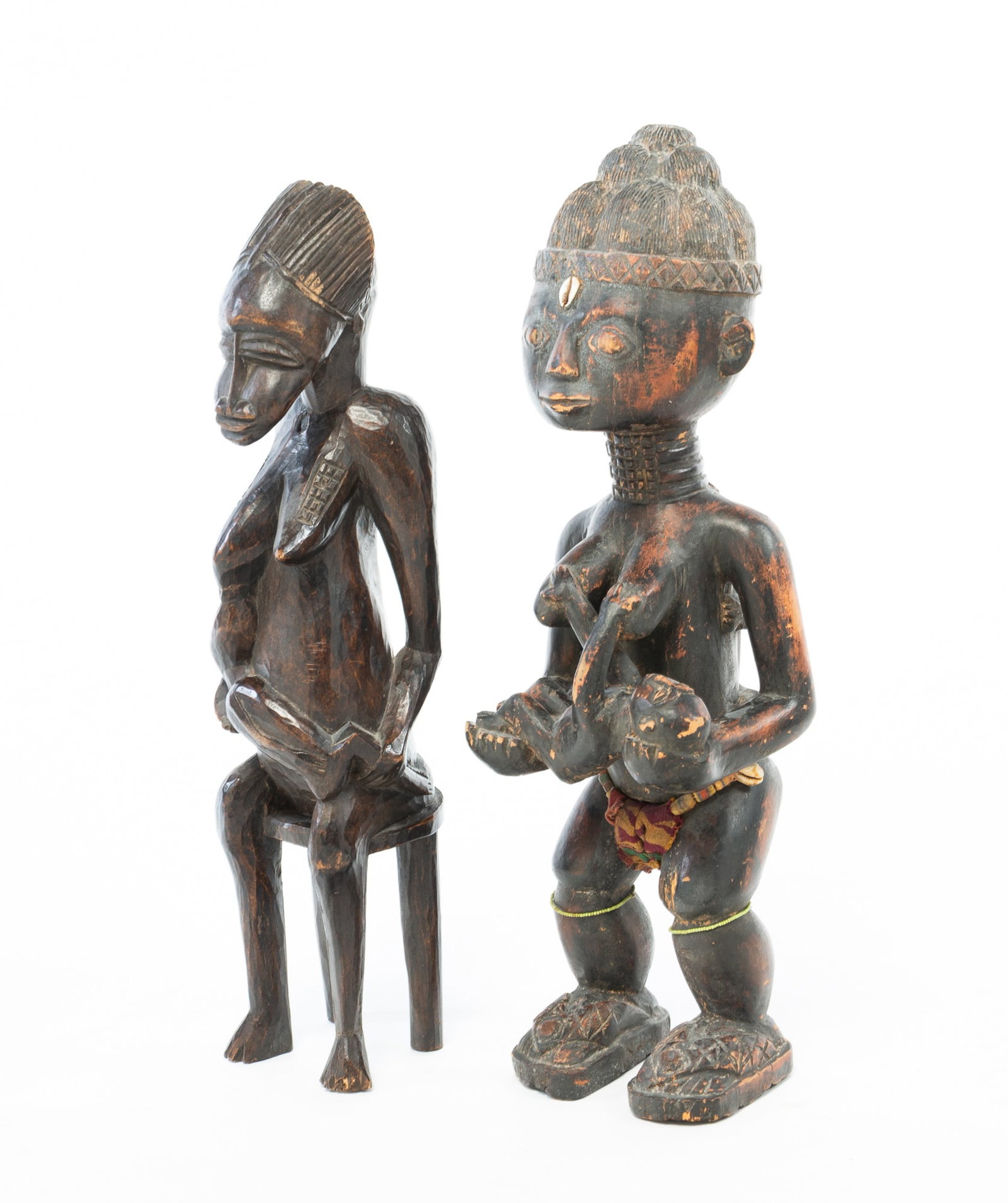 PAIR OF CARVED WOOD FIGURES OF MOTHERS AND CHILDREN.: PAIR OF CARVED WOOD FIGURES OF MOTHERS AND CHILDREN. Africa, 20th Century. Hardwood. The first from the Ivory Coast, depicts a nursing mother seated on a stool. 21.5"h., and the second depicts a stand