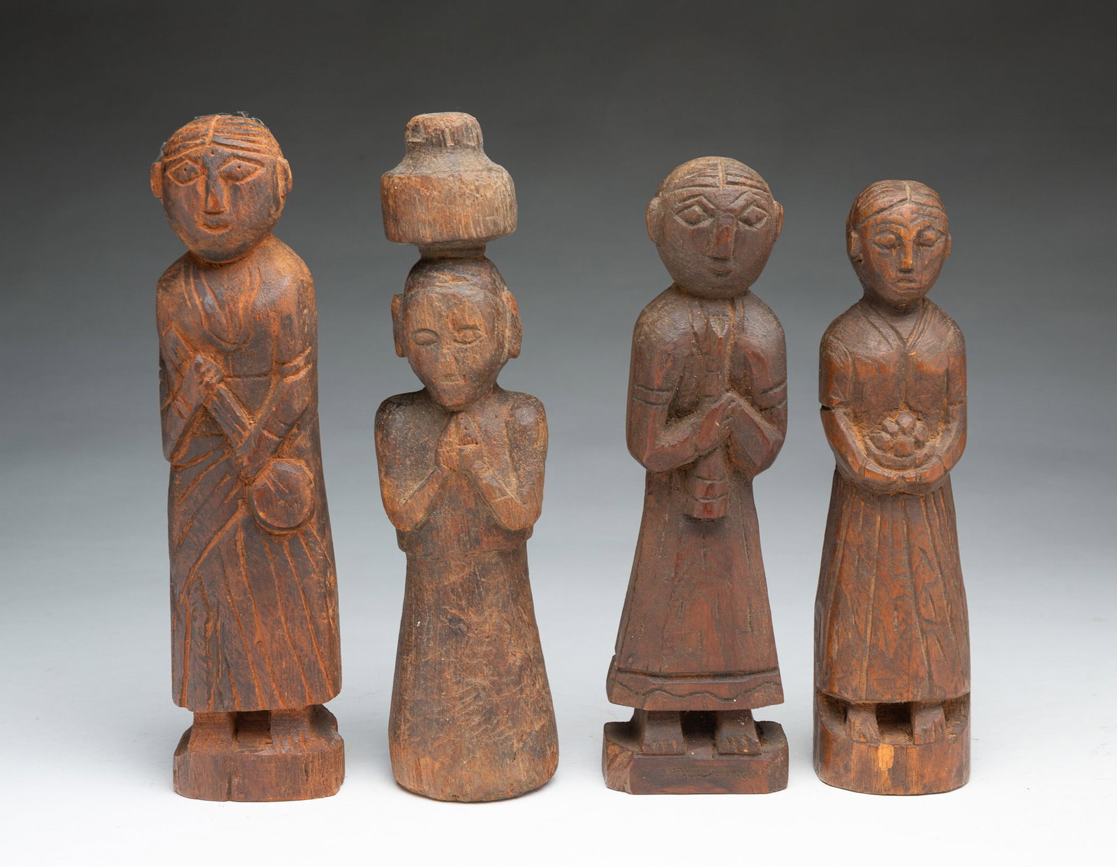 FOUR CARVED WOODEN FIGURES.: FOUR CARVED WOODEN FIGURES. European or Asian, 19th Century. Four carved figures, three on plinth bases, each with hair parted in the middle and diamond-shaped eyes, one holding a stringed