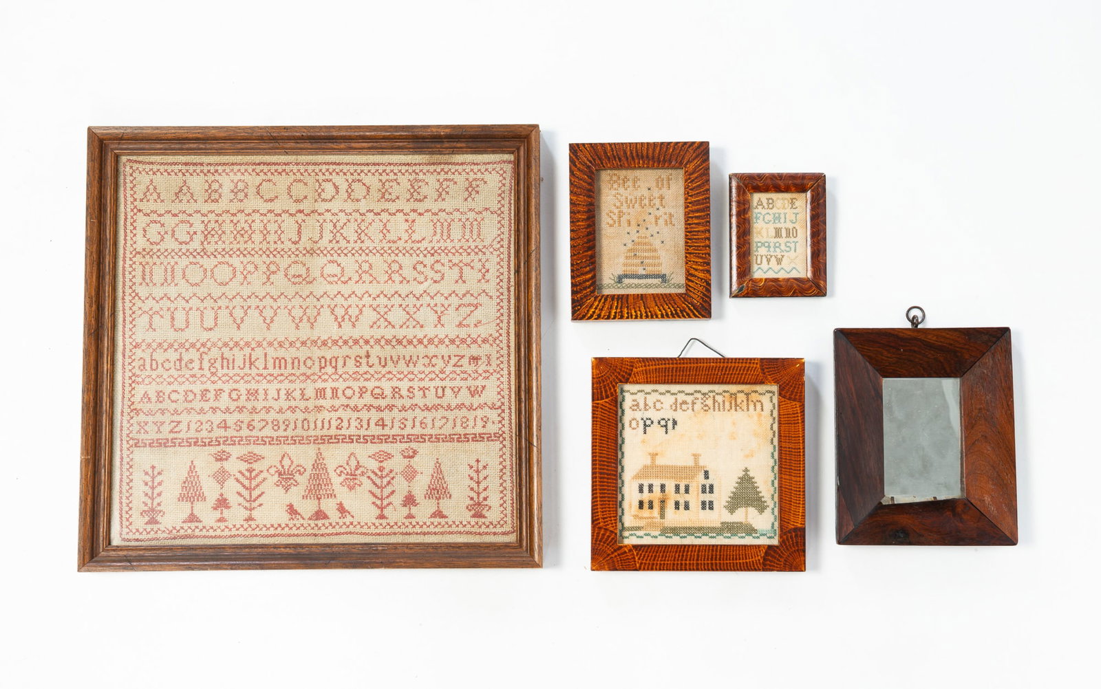FIVE FRAMED DECORATIVE ITEMS.: FIVE FRAMED DECORATIVE ITEMS. American, Late 19th or Early 20th Century. Three diminutive reproduction samplers in grain-decorated frames, 6.25" square, 5.25"h. 4.25"w. and 3.75"h. 2.75"w., a diminuti