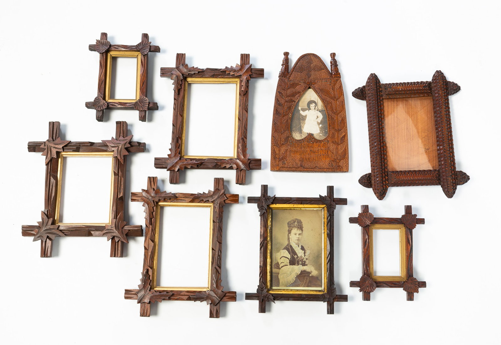 EIGHT PICTURE FRAMES.: EIGHT PICTURE FRAMES. American, Late 19th or Early 20th Centuries. A chip carved with an arched top, carved finials, and a heart-shaped opening, 10.25"w. A tramp art frame, 8.5"h. 10.5"w., and six