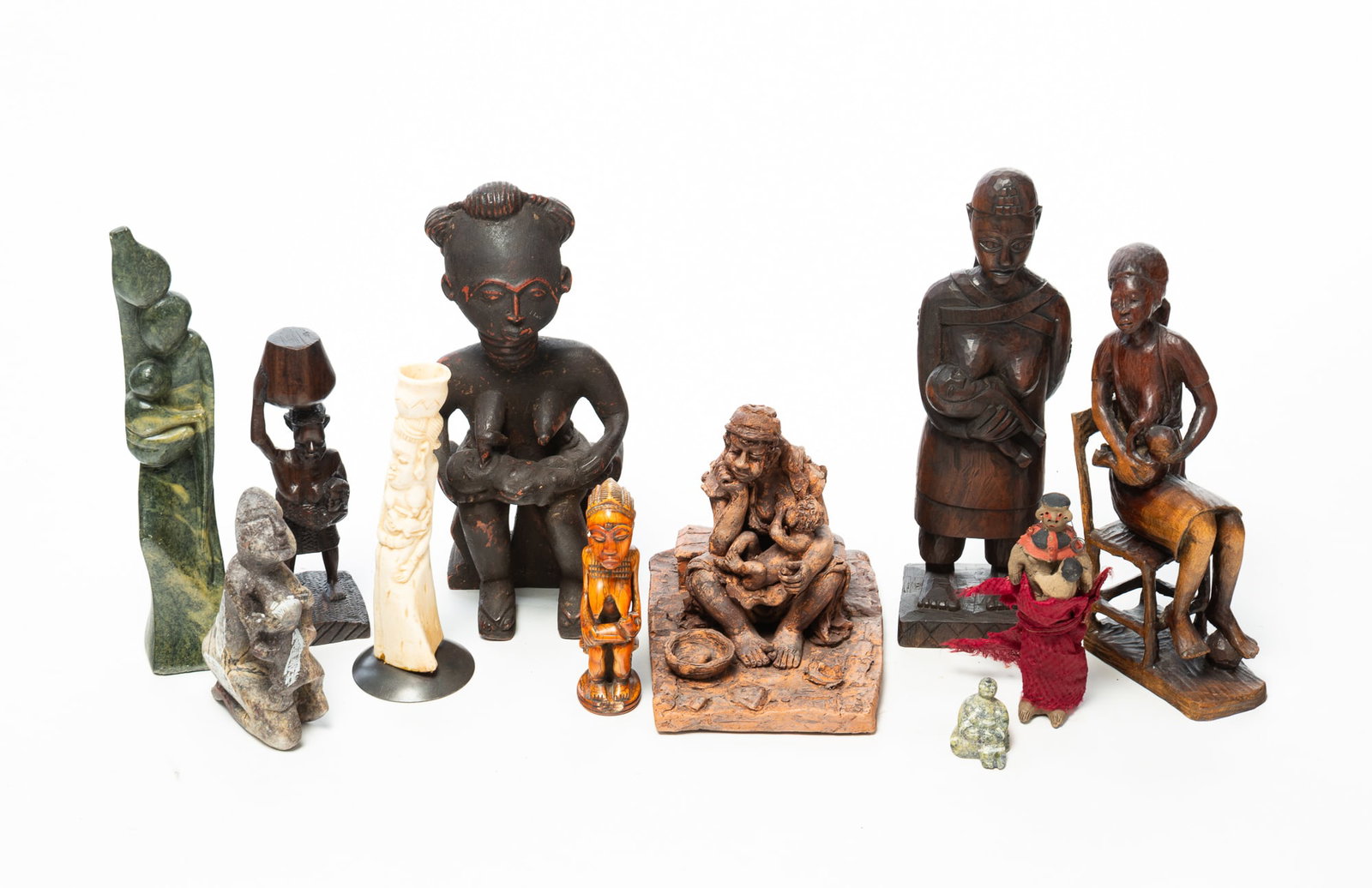 ELEVEN FIGURINES OF NURSING MOTHERS.: ELEVEN FIGURINES OF NURSING MOTHERS. Africa, Asia, and other nationalities, 20th Century. Comprising carved wood, carved stone, sculpted clay, and a bone example. One terracotta figure signed
