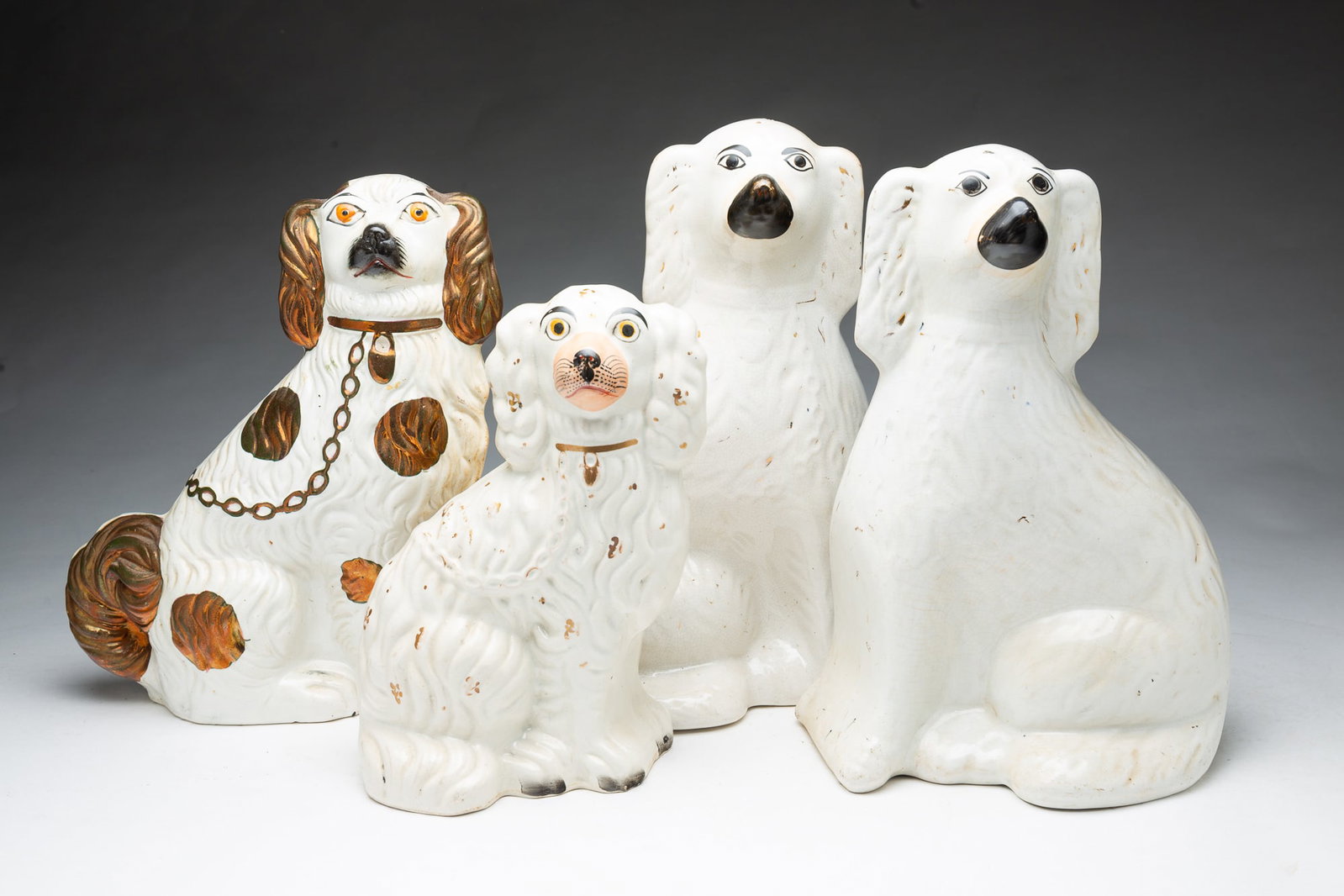 FOUR STAFFORDSHIRE SEATED SPANIELS.: FOUR STAFFORDSHIRE SEATED SPANIELS. England, Mid-19th Century. A male and female pair, 13"h., and 12.75"h., a single, 10"h., and one with copper luster highlights, 12"h. Provenance: The Lifetime