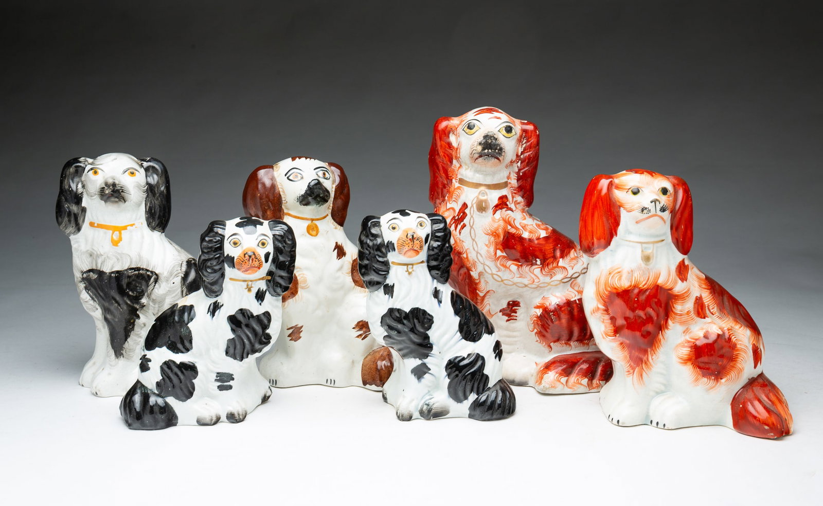 SIX STAFFORDSHIRE SEATED SPANIELS.: SIX STAFFORDSHIRE SEATED SPANIELS. England, Mid-19th Century. A male and female pair with black highlights, 6.5"h., a single with black highlights, 8"h., two rust colored Blenheim spaniels, 9"h., and
