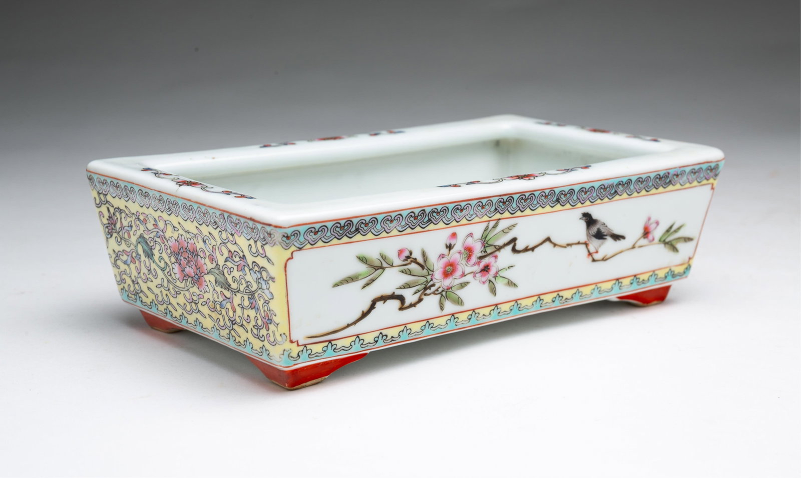 FAMILLE ROSE RECTANGULAR FOOTED PORCELAIN PLANTER.: FAMILLE ROSE RECTANGULAR FOOTED PORCELAIN PLANTER. China, 20th Century. Rectangular footed planter, Famille Rose pattern on two ends and birds on branches with flowers on the others. Reign mark to