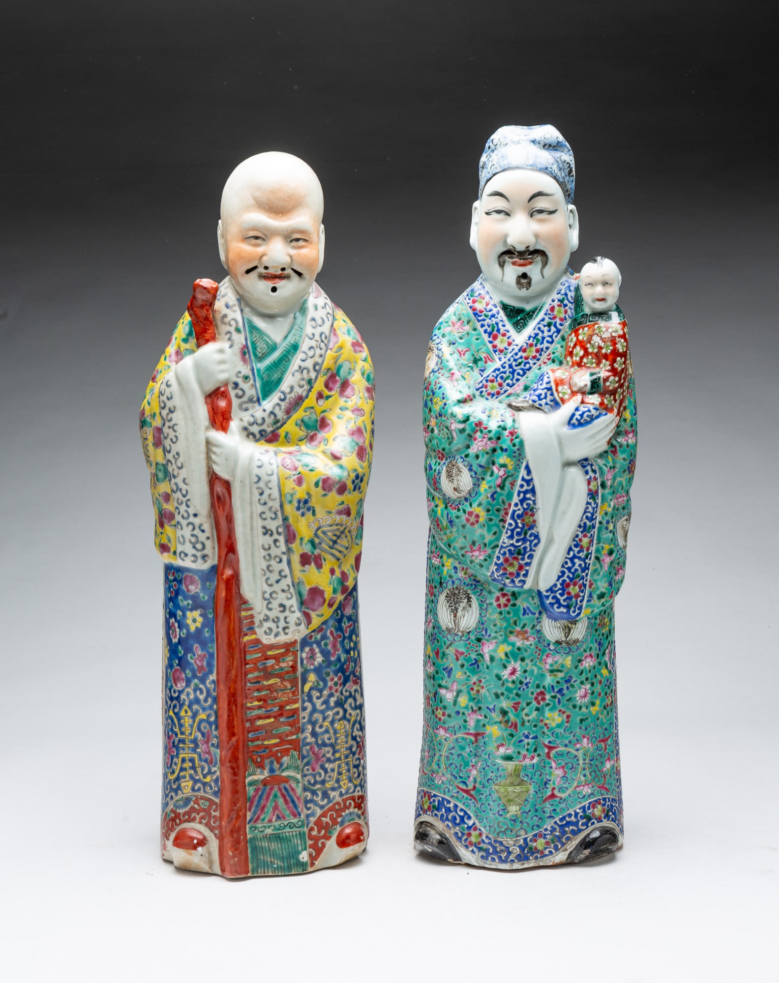 PAIR OF LARGE CHINESE FAMILLE ROSE PORCELAIN FIGURES.: PAIR OF LARGE CHINESE FAMILLE ROSE PORCELAIN FIGURES. China, Late 19th and early 20th Century. Showing Luxing and Shou Lao in heavily patterned robes, one holding a child and the other, a staff.