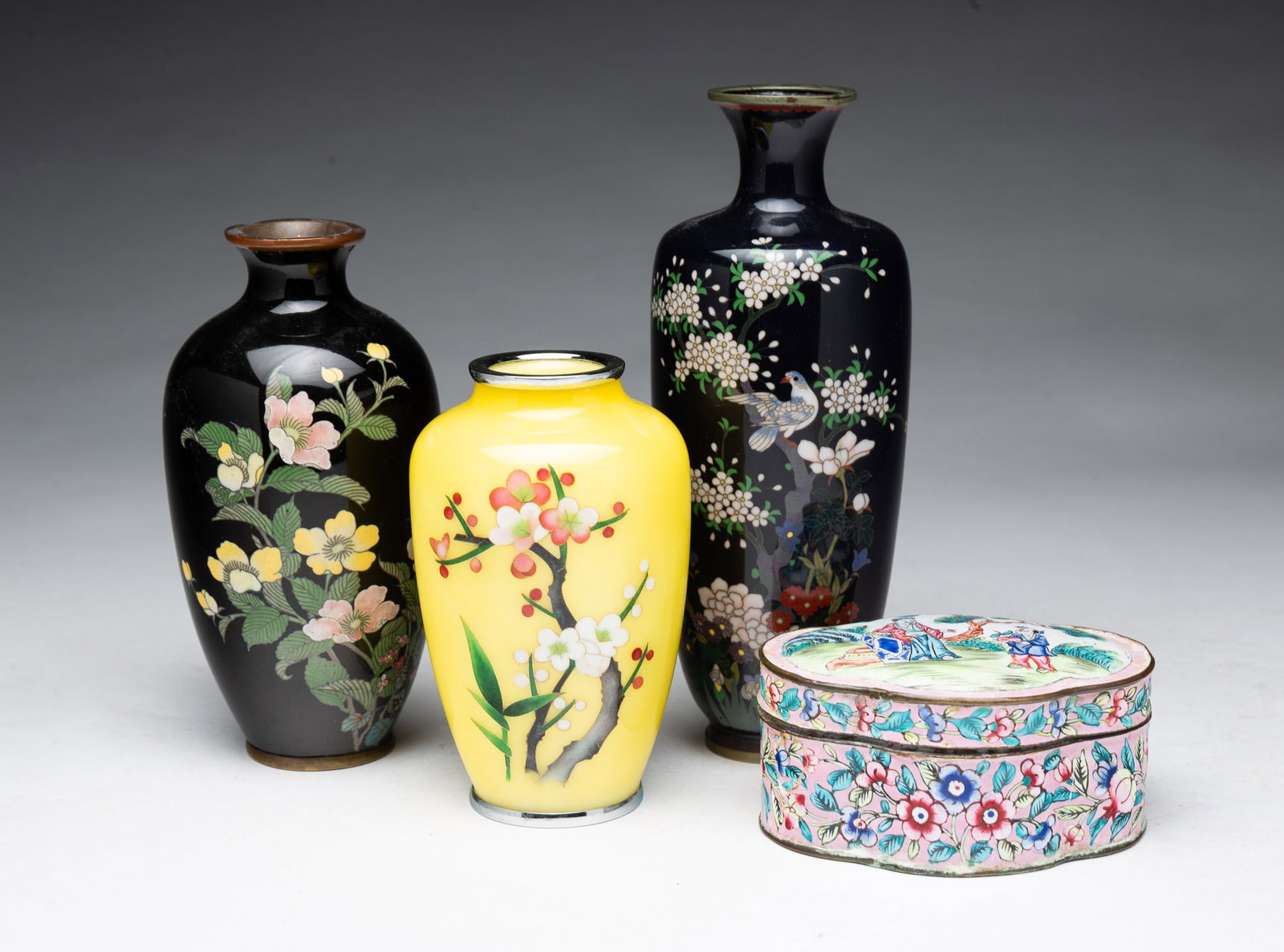 FOUR ASIAN CLOISONNE VESSELS.: FOUR ASIAN CLOISONNE VESSELS. China and Japan, 20th Century. Two dark vases with floral decoration, 5.75"h. and 7.25"h., a yellow ground vase with flower decoration, and a Canton lidded enamel box