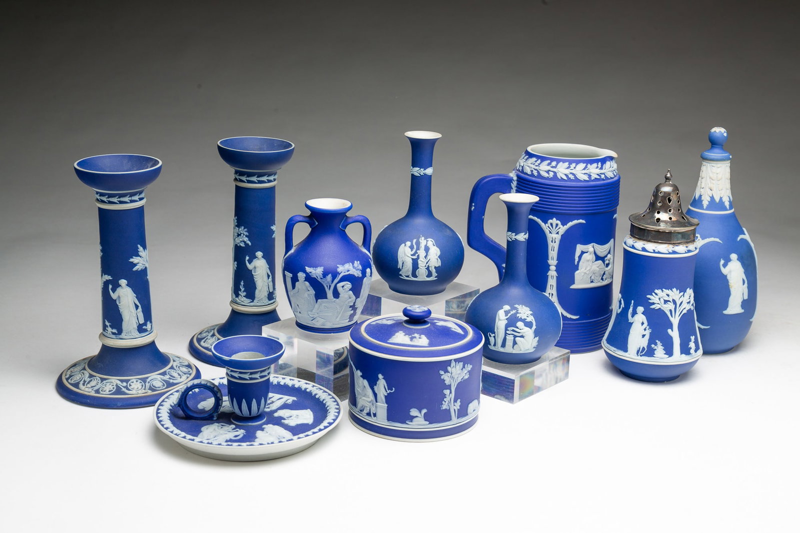 GROUP OF WEDGWOOD BLUE DIP JASPERWARE ITEMS.: GROUP OF WEDGWOOD BLUE DIP JASPERWARE ITEMS. English, 19th Century. All impressed WEDGWOOD marks. A pair of candlesticks, 7"h., a pair of bud vases with bulbous bases, 5"h., a chamber stick, 2.5"h.,