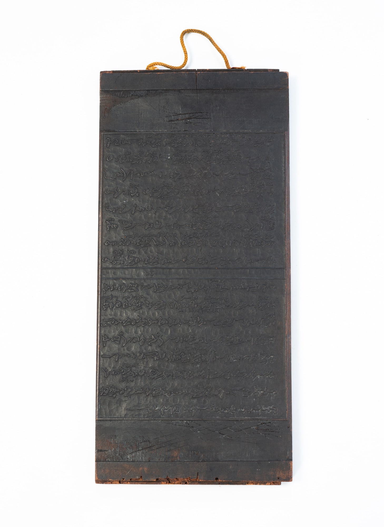 JAPANESE DOUBLE-SIDED WOODBLOCK PRINTING PLATE.: JAPANESE DOUBLE-SIDED WOODBLOCK PRINTING PLATE. Japan, 20th Century. Rectangular plate having raised letters on both sides, with a gold cord on top for hanging. 16"h. 7.5"w.