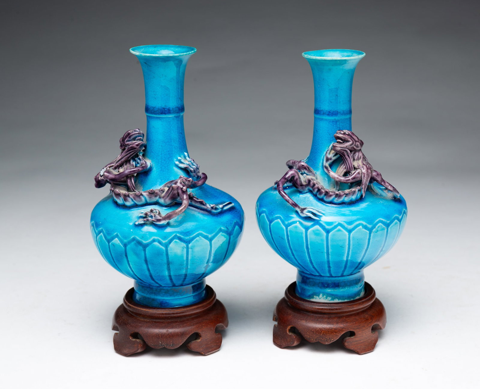 PAIR OF JAPANESE AWAJI DRAGON VASES ON STANDS.: PAIR OF JAPANESE AWAJI DRAGON VASES ON STANDS. Japanese, 20th Century. Blue glazed vases with tapered necks, flared rims, and bulbous bottoms with purple dragons climbing the vase. On wood stands.