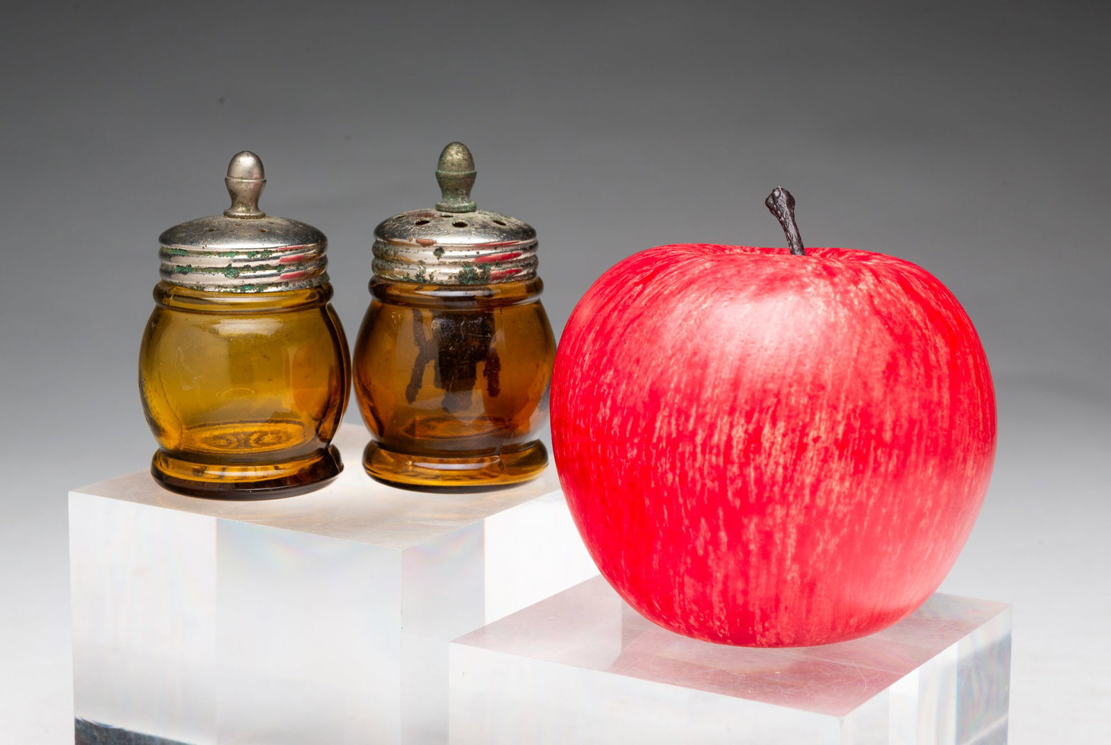 TWO AMBER GLASS CHRISTMAS SALTS.: TWO AMBER GLASS CHRISTMAS SALTS. American, Late 19th or Early 20th Century. Each with a silver tone metal lid with acorn finial above an amber glass body. One with agitator, 2.75"h. Provenance: The