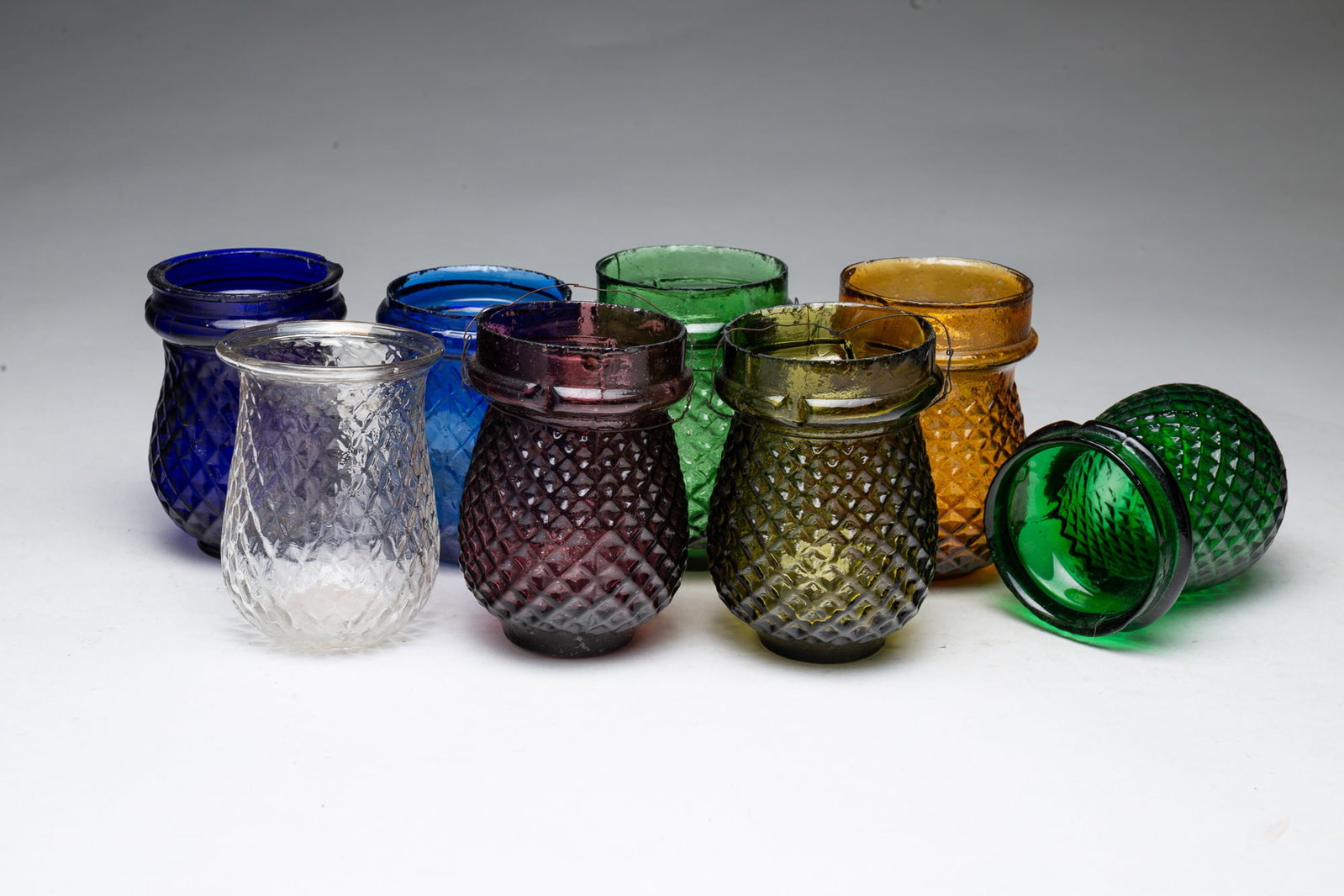 EIGHT POLYCHROME CHRISTMAS TREE LANTERNS.: EIGHT POLYCHROME CHRISTMAS TREE LANTERNS. American, Late 19th Century. One amber, two blue, one amethyst, one clear, and three green, all with textured quilted pattern. 4"h. to 3.75"h. Provenance: