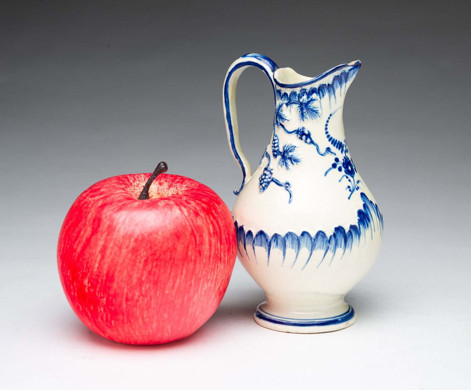 MINIATURE WORCESTER BLUE AND WHITE MOLDED PORCELAIN PITCHER.: MINIATURE WORCESTER BLUE AND WHITE MOLDED PORCELAIN PITCHER. England, 18th Century. Of bottle form with a pinched spout, applied handle, and flared foot, decorated with molded feather-edge motifs,