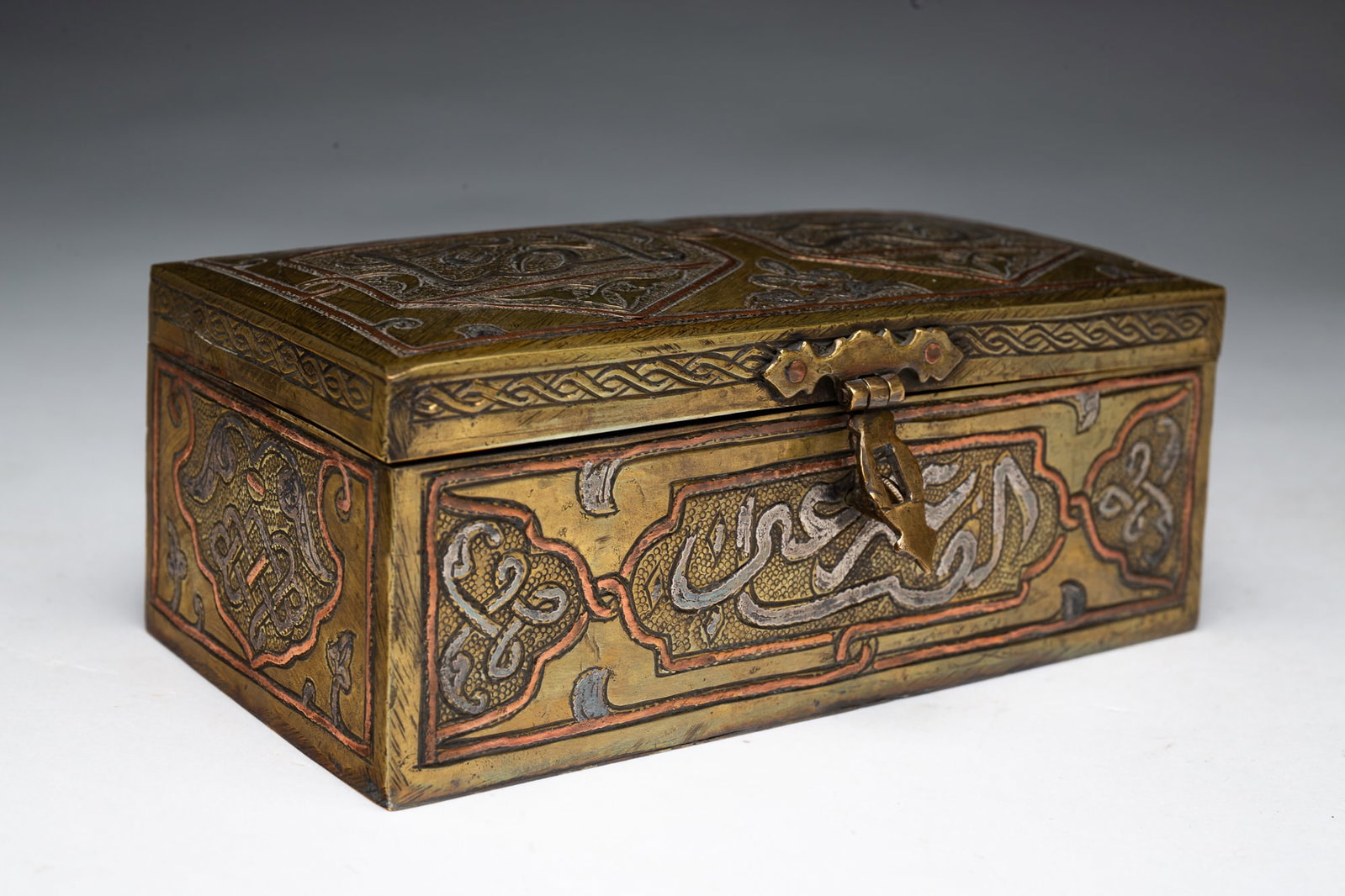 PERSIAN SILVER AND COPPER INLAID BOX.: PERSIAN SILVER AND COPPER INLAID BOX. Asia, 19th Century. Mixed metal rectangular box with calligraphy and geometric decoration, lock hasp, and interior is lined with wood. 2.25"h. 6"w.