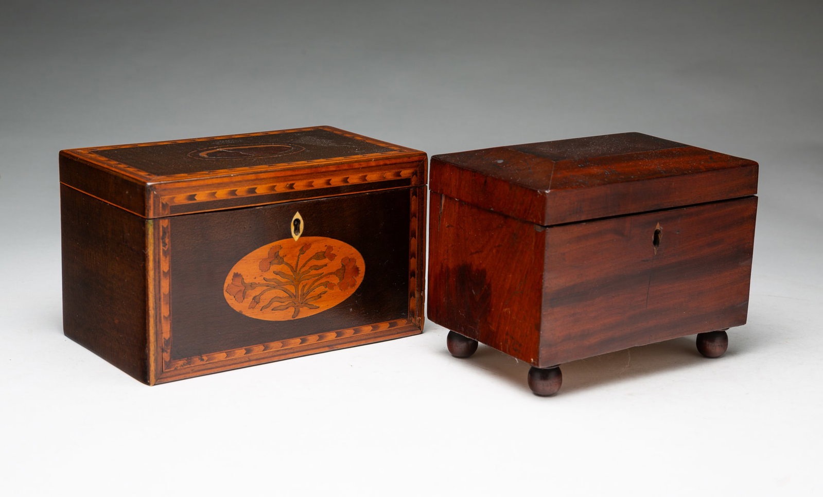 TWO ENGLISH TEA CADDIES.: TWO ENGLISH TEA CADDIES. 19th Century. A mahogany-veneered caddy resting on four bun feet, and a hinged lid that opens to an interior well, 4.5"h. 6"w. And a veneered and marquetry caddy of