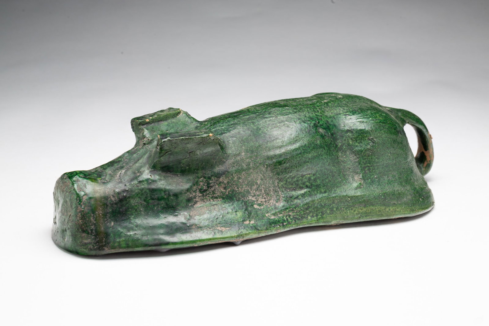 GLAZED POTTERY RECUMBENT PIG FOOD MOLD.: GLAZED POTTERY RECUMBENT PIG FOOD MOLD. American, 19th Century. Depicting a recumbent pig with green-glazed exterior and mostly yellow-glazed interior, 3.25"h. 6.5"w. 13.5"l. Provenance: The Lifetime