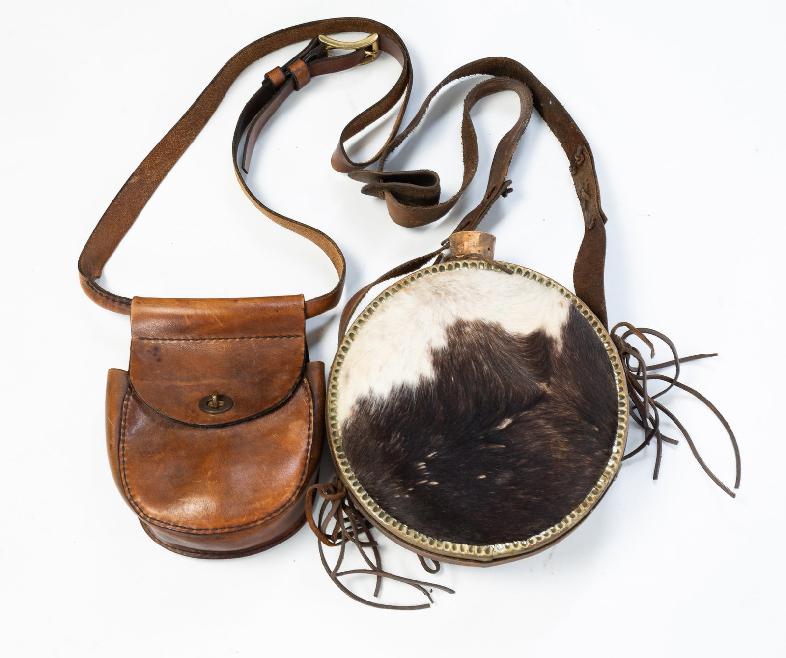 LEATHER CARTRIDGE BAG AND A HAIR-COVERED CANTEEN.: LEATHER CARTRIDGE BAG AND A HAIR-COVERED CANTEEN. American, Late 19th or early 20th Century. A round canteen with leather strap and covered in black and white cow fur, 25"l. 9"w. And a leather
