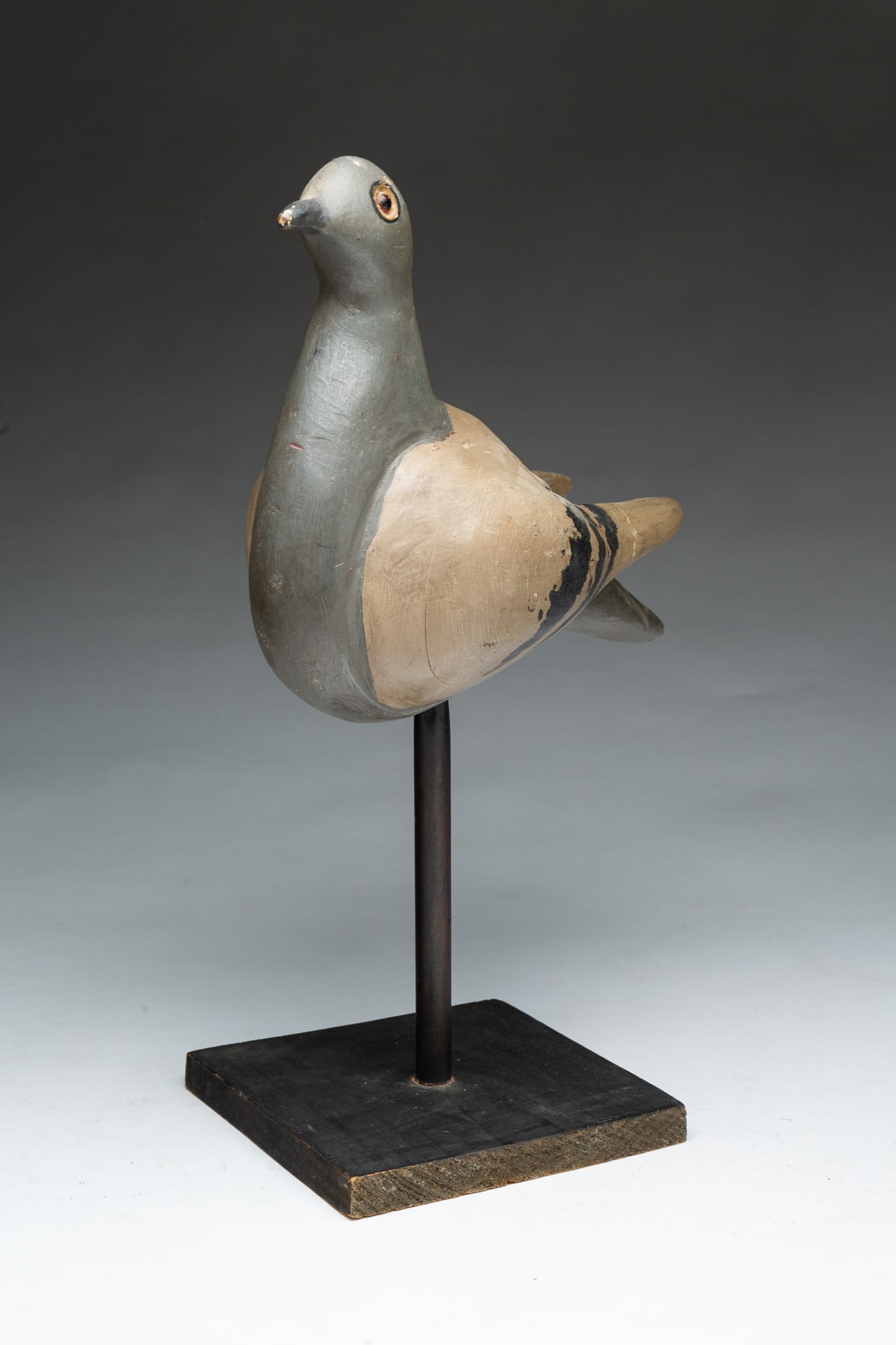 FINE FOLK ART CARVED AND PAINTED WOODEN PIGEON DECOY ON STAND.: FINE FOLK ART CARVED AND PAINTED WOODEN PIGEON DECOY ON STAND. American, Late 19th or Early 20th Century. Painted pine pigeon with pegged construction, inset glass eyes, and on a black-painted wooden 