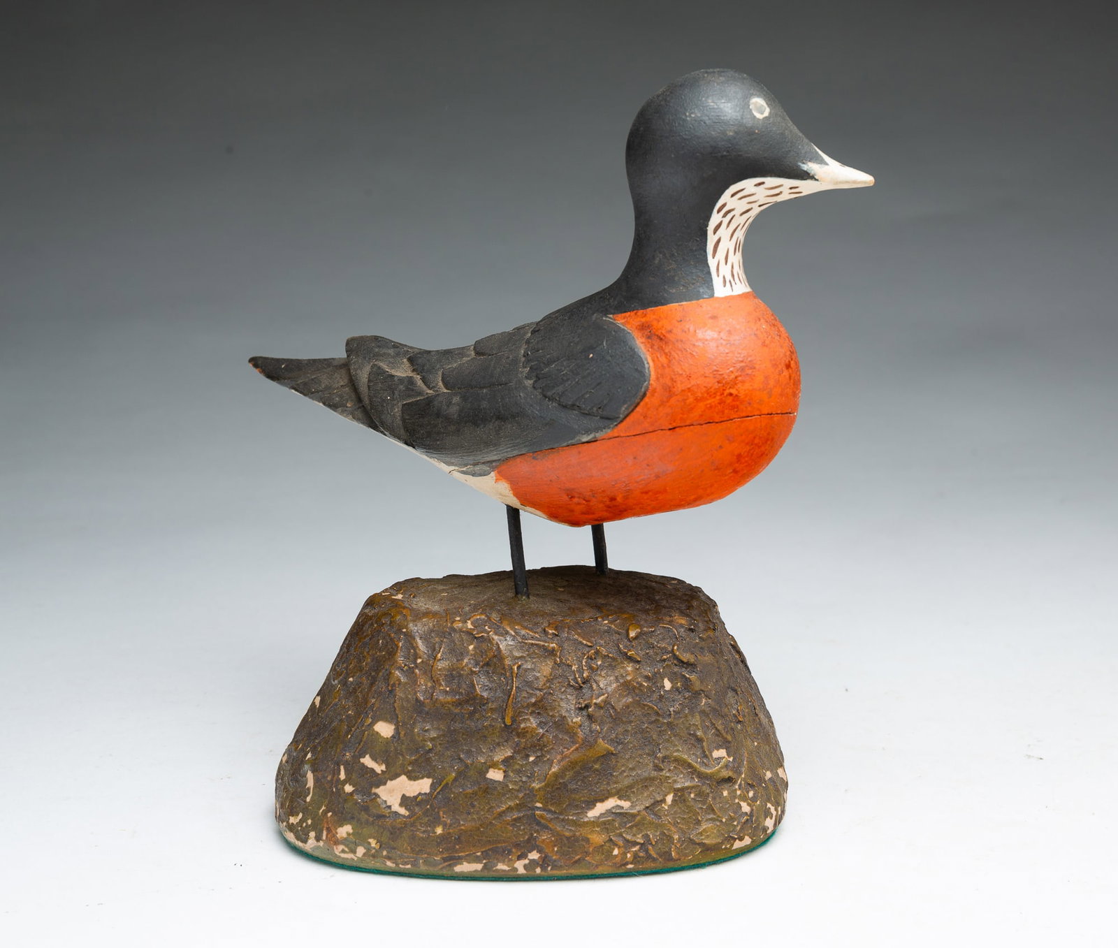 FOLK ART CARVED AND PAINTED BIRD OR DUCK DECOY.: FOLK ART CARVED AND PAINTED BIRD OR DUCK DECOY. American, 20th Century. Bird painted with black head, back, and tail, white and brown beak and throat, and an orange belly, standing on two metal legs m