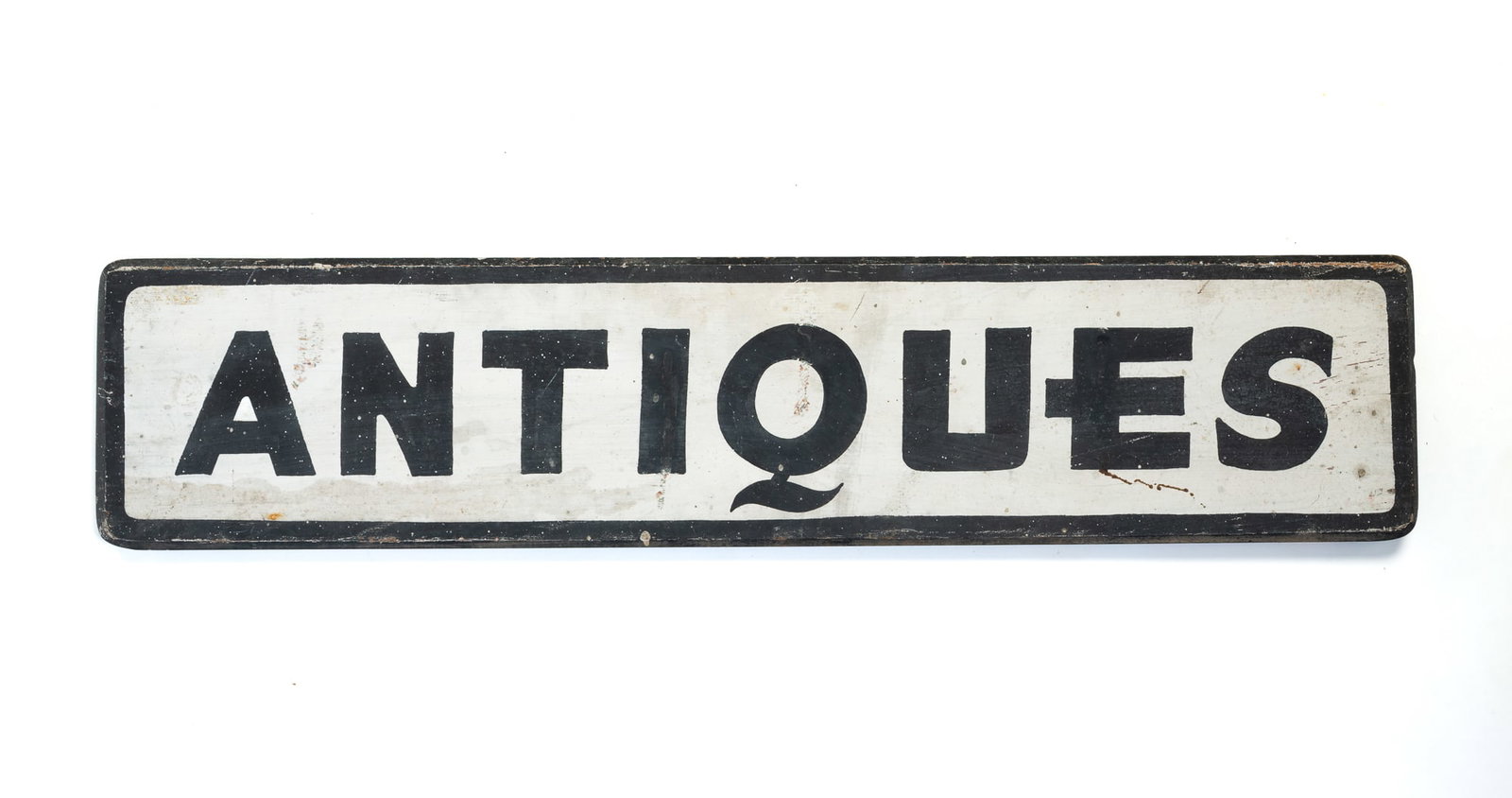 PAINTED WOOD "ANTIQUES" TRADE SIGN.: PAINTED WOOD "ANTIQUES" TRADE SIGN. American, 20th Century. Black letters and border painted on a white ground, with a chamfered front edge and a hook on verso for hanging. 7"h. 31.25"w.