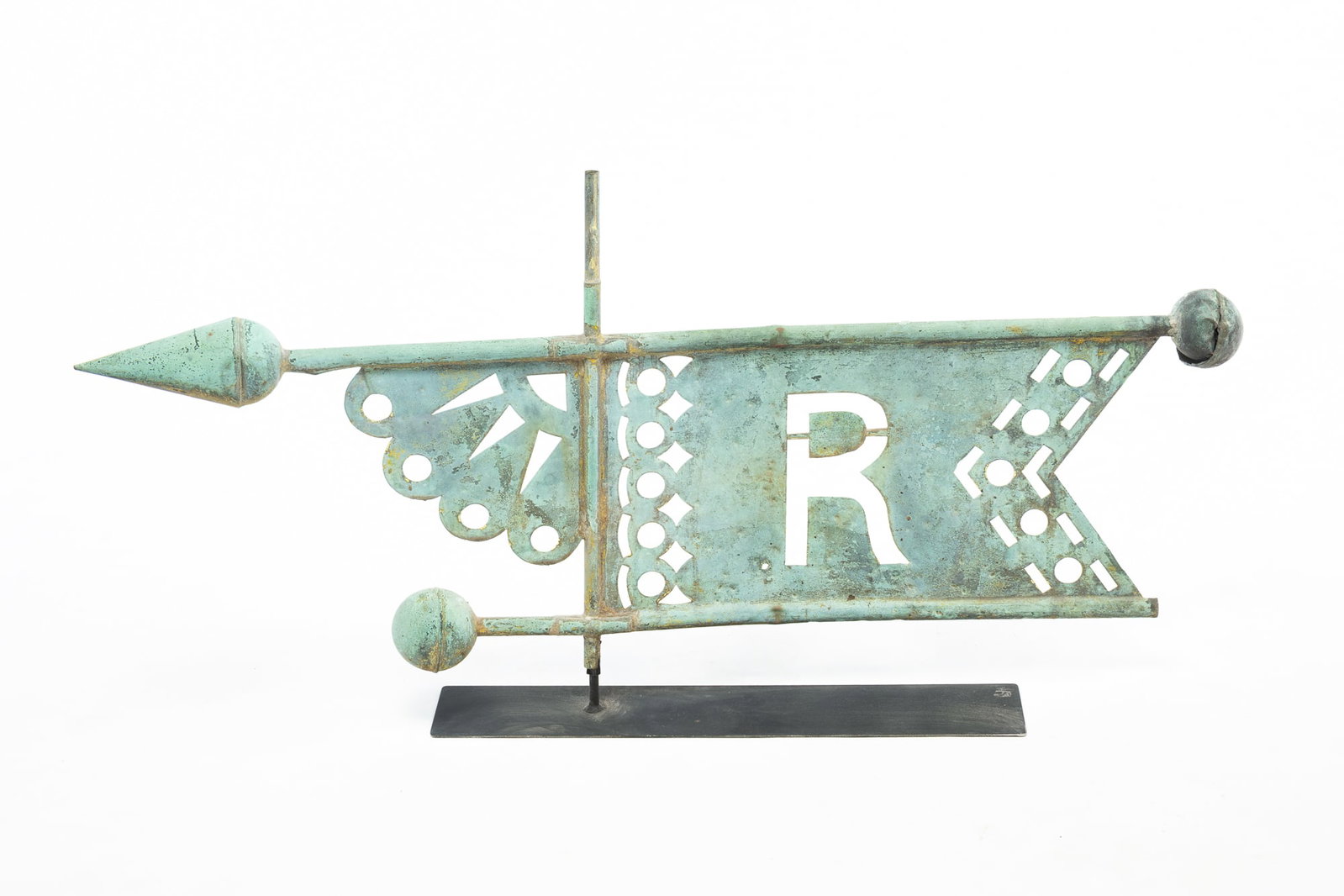"R" BANNER WEATHERVANE.: "R" BANNER WEATHERVANE. American, 19th Century. Copper. Banner form with scalloped end, geometric patterns, "R" to center, and on a contemporary stand. 21"h. 42"w. Provenance: From the Lifetime